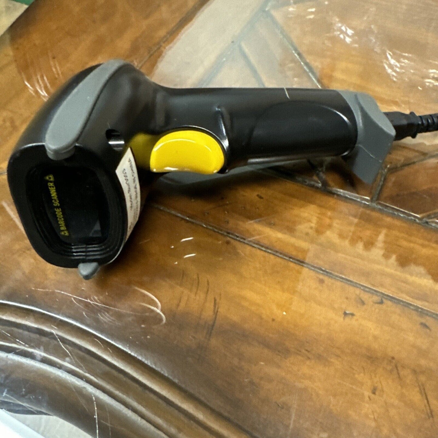 Nadamoo BUR3003 handheld black wireless barcode scanner with yellow trigger resting on wooden surface