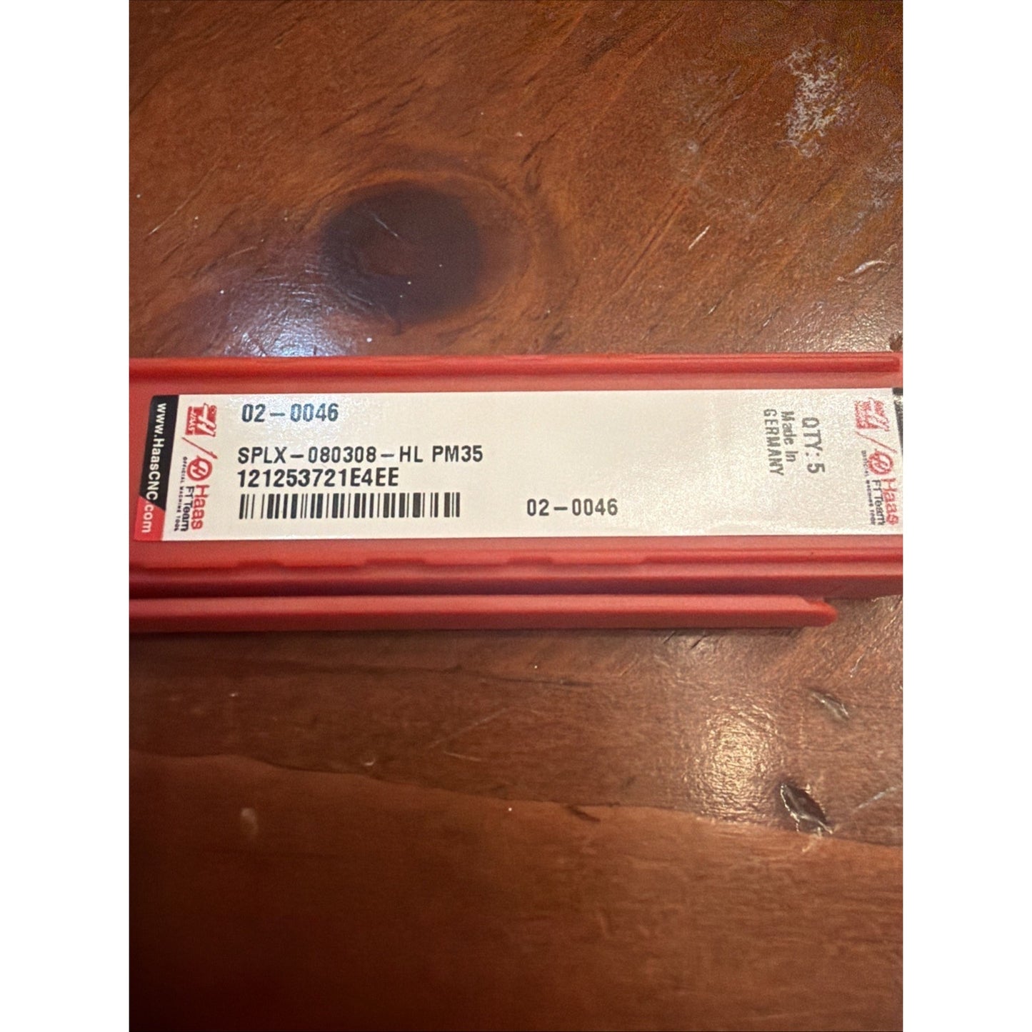 Long red plastic container with a white label showing product code "SPLX-080308-HL PM35," quantity "5," barcode, and "Made in Germany," placed on a wooden surface.