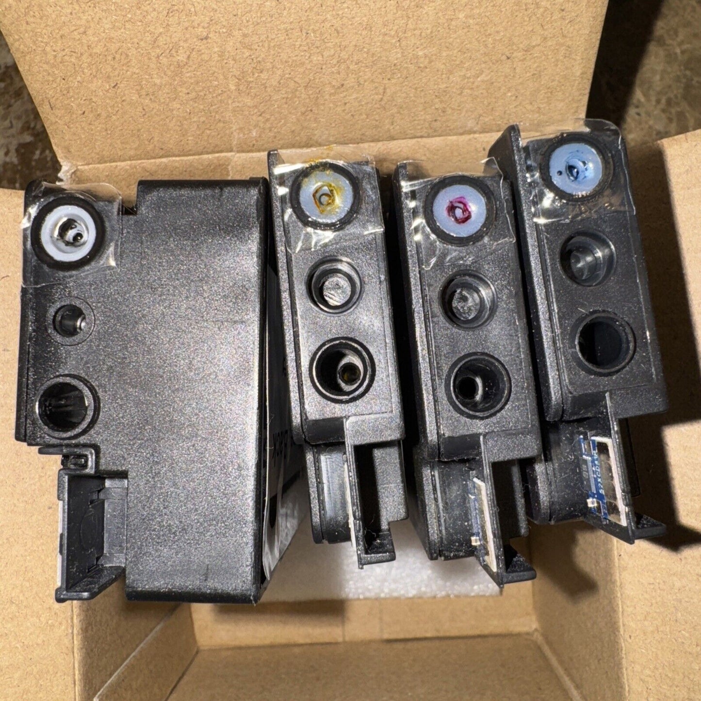 Set of four 952 XL ink cartridges in black, cyan, magenta, and yellow with broken seals inside a cardboard box