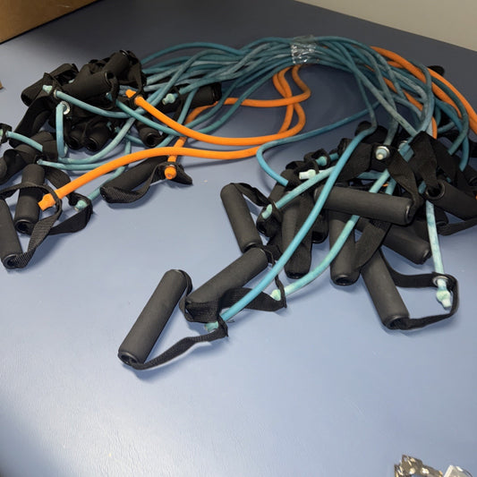 Set of 18 multicolor fitness resistance bands with black foam handles arranged on flat surface for home workouts