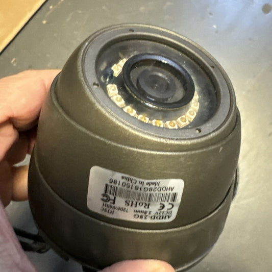 Close-up of hand holding 720p/960 dome security camera with visible lens and infrared LEDs on gray background