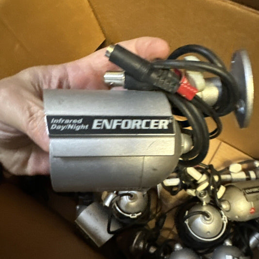 Hand holding one of 11 Enforcer EV-1323C12DW infrared day/night home surveillance cameras with wiring bundle