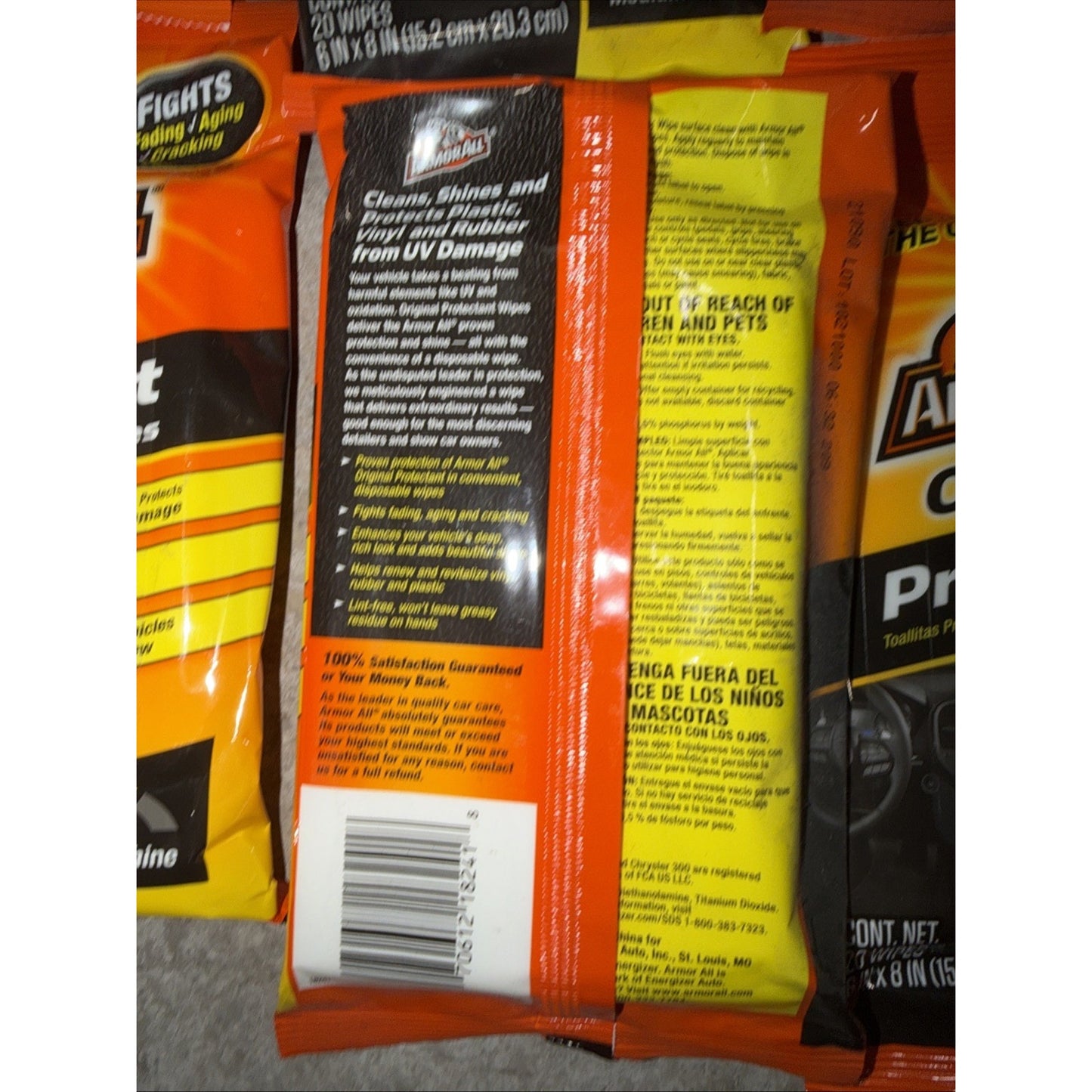 Orange and yellow plastic packaging for cleaning wipes with text detailing usage instructions, safety warnings, and product benefits, shown on a textured surface.