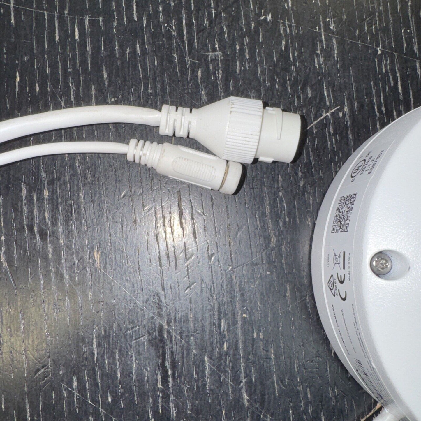 Close-up of Hikvision DS2CD2123G0I outdoor IR dome camera connectors and part of camera housing on black surface