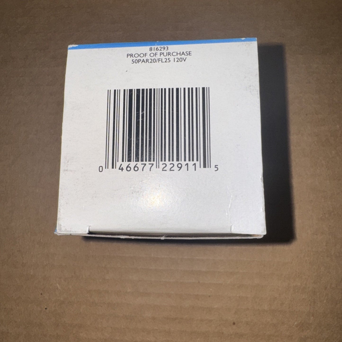 White product box with a barcode and printed text indicating proof of purchase and technical details, placed on a brown cardboard surface.