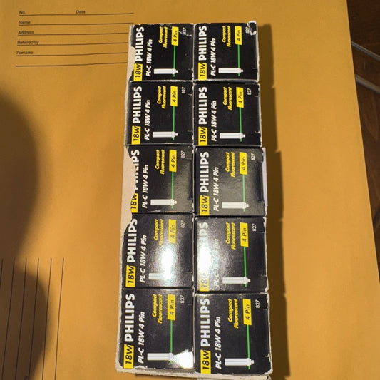 Ten packs of Philips 18W PL-C 4 pin compact fluorescent lamp bulbs in original packaging on a brown surface