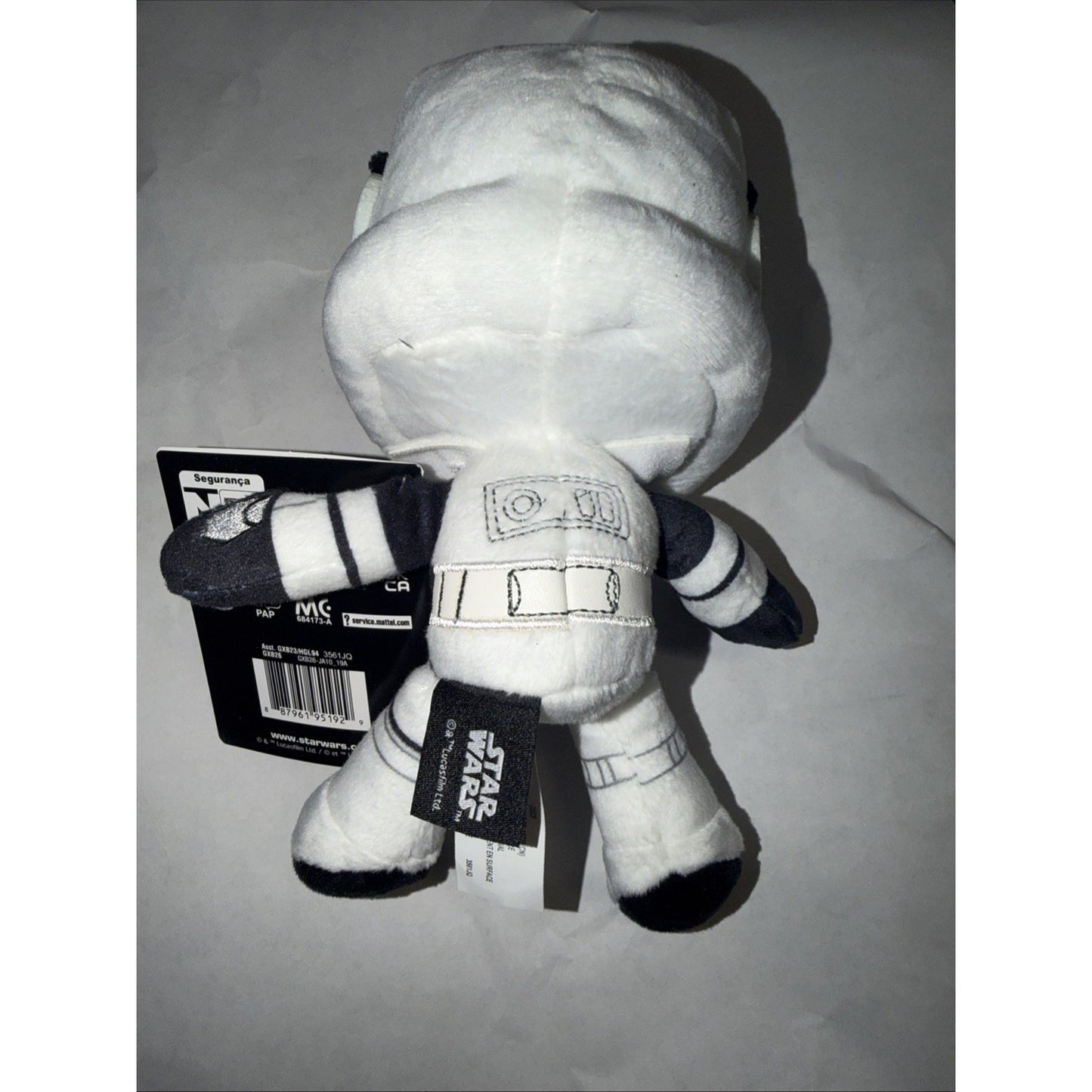 Small plush toy resembling a white Star Wars stormtrooper character with black and gray details, shown from the back with attached tags against a plain background.