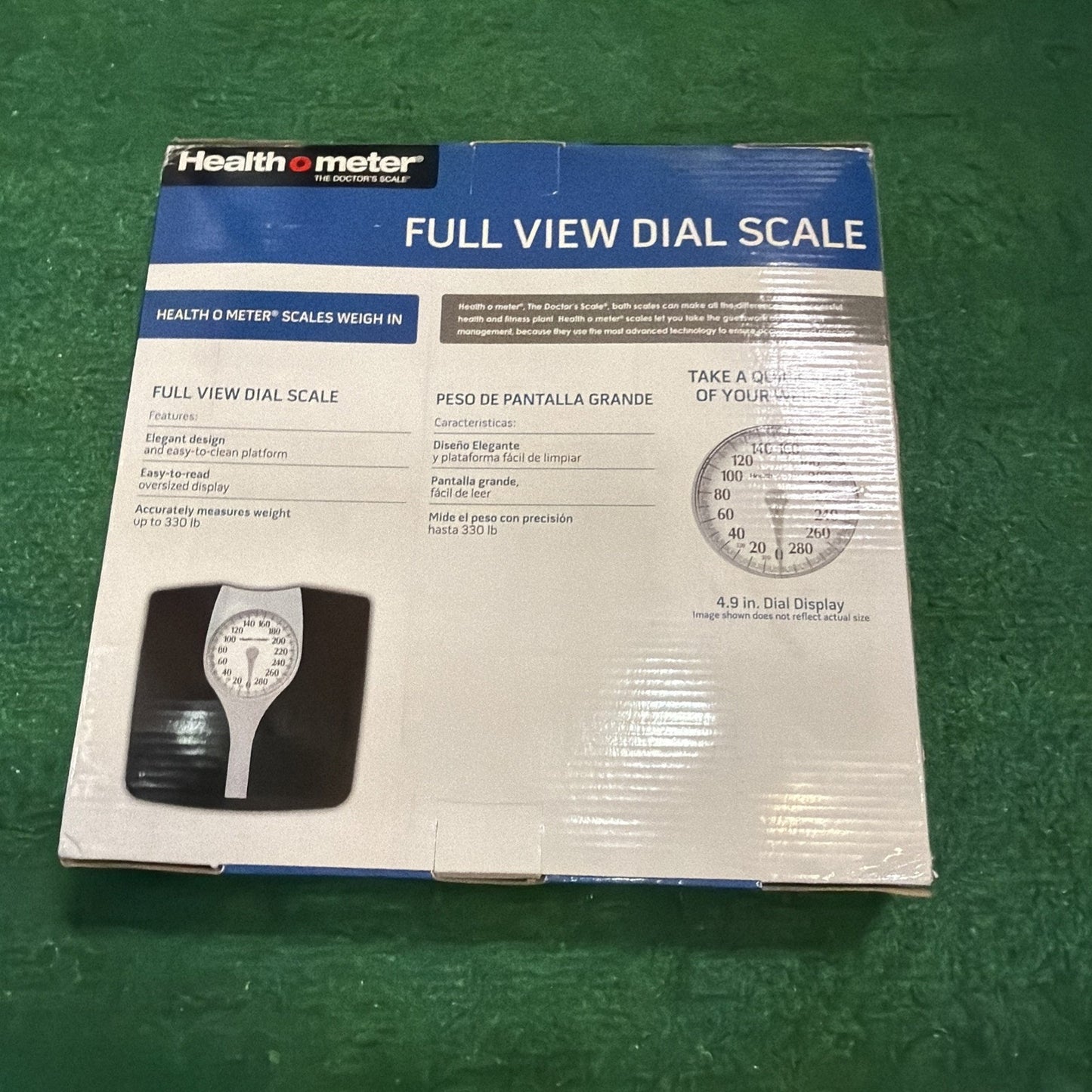 Packaging box for a Health o meter full view dial scale with features listed including elegant design, easy-to-read dial, and weight measurement up to 330 pounds on a green surface.