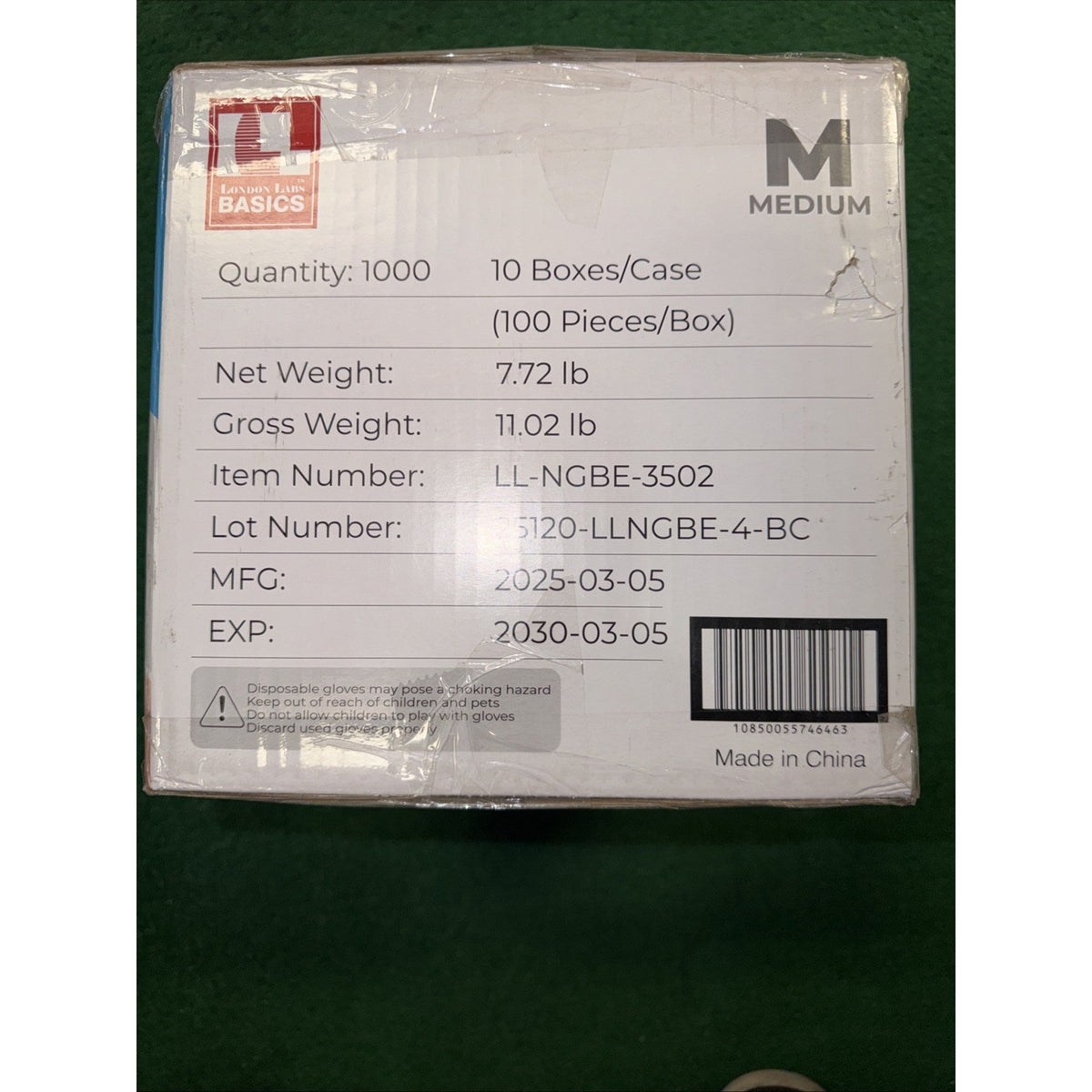 White product box displaying quantity, weight, item and lot numbers, manufacturing and expiration dates, barcode, and "Medium" size label on a green surface.