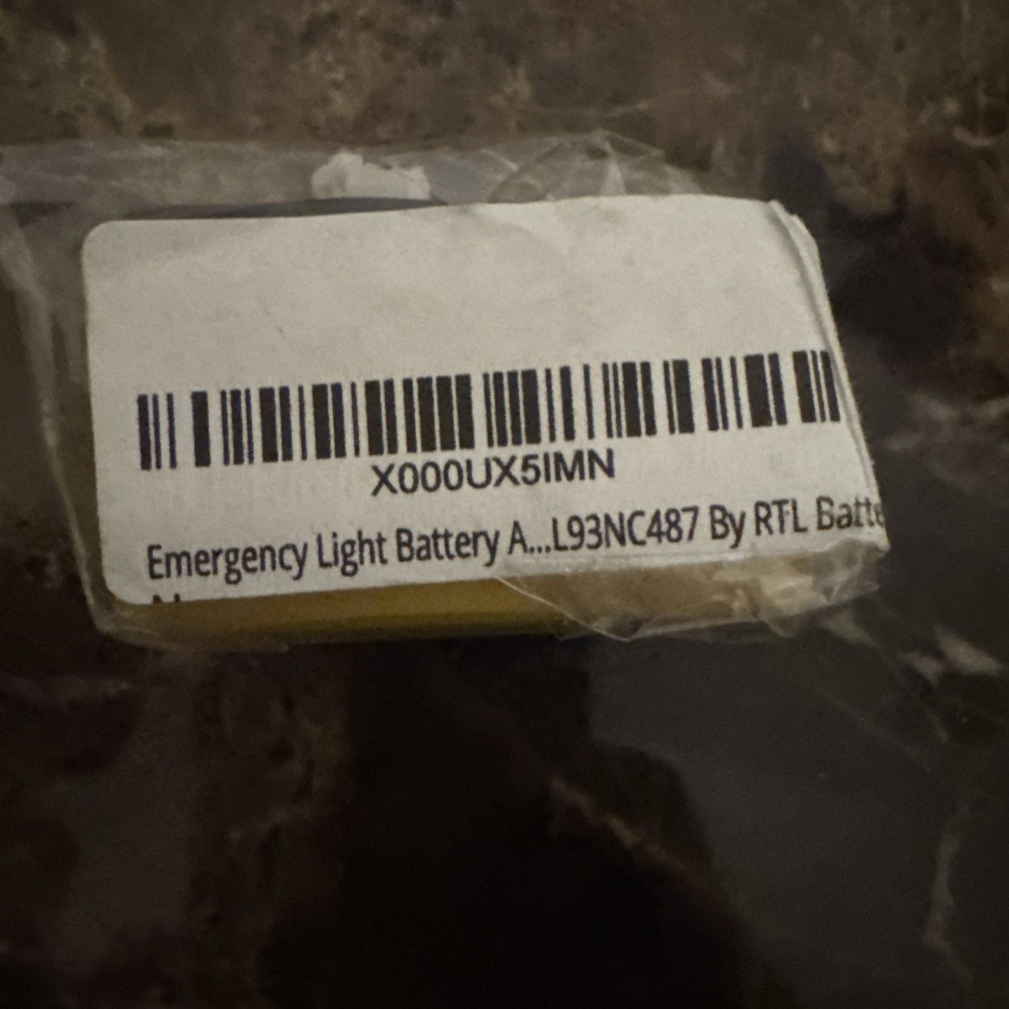 Close-up of 4.8V 700mAH Ni-Cd rechargeable emergency light battery with barcode label and partial text on plastic wrap