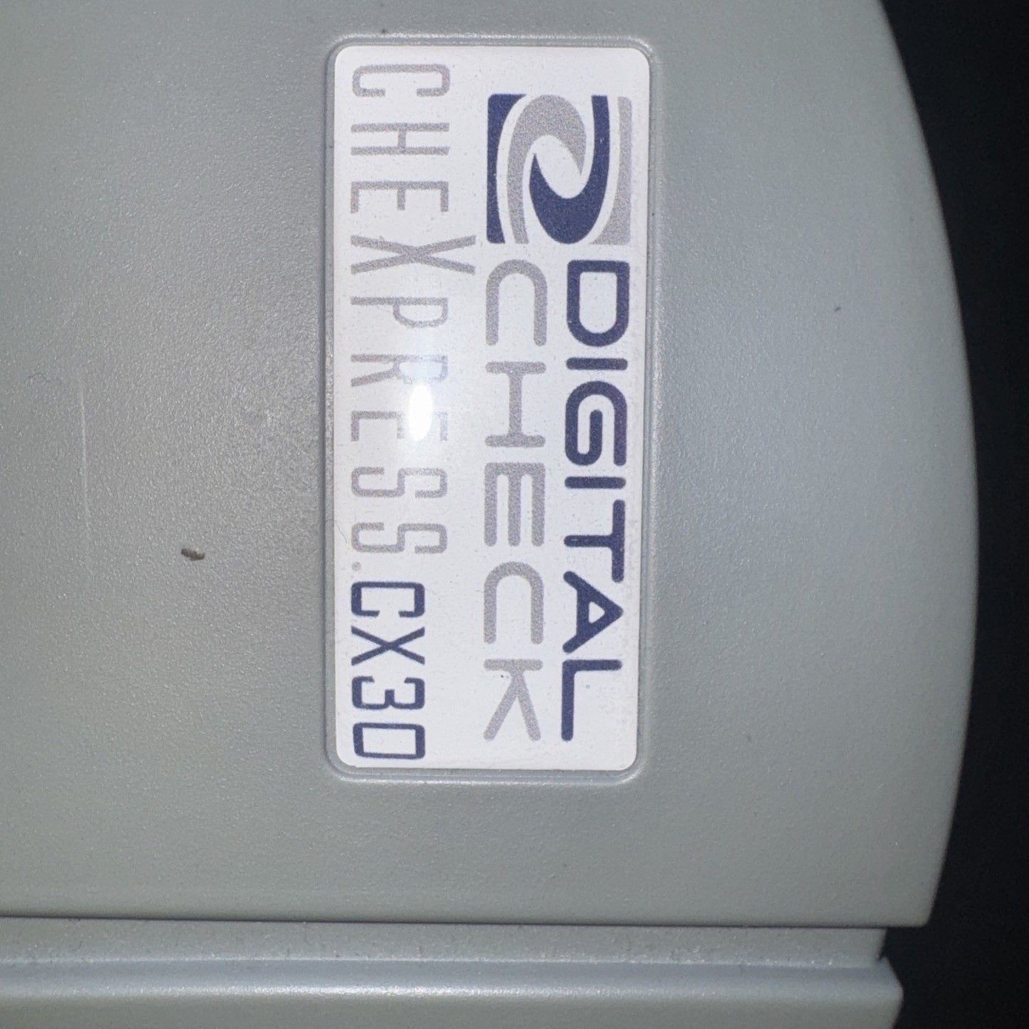 Close-up of Digital Check CheXpress CX30 inkjet check scanner logo label on gray plastic housing