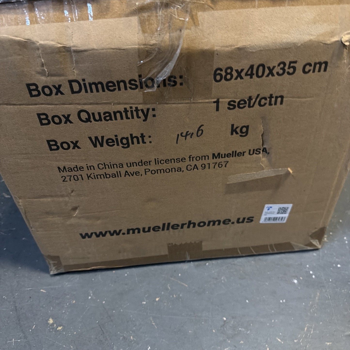 Close-up of a cardboard shipping box with printed dimensions 68x40x35 cm, quantity of 1 set per carton, handwritten box weight of 14.6 kg, and manufacturer information including a website URL.