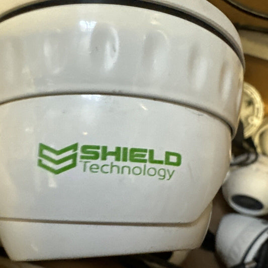 White analog CCTV dome camera with Shield Technology logo printed on the side showing security device close-up