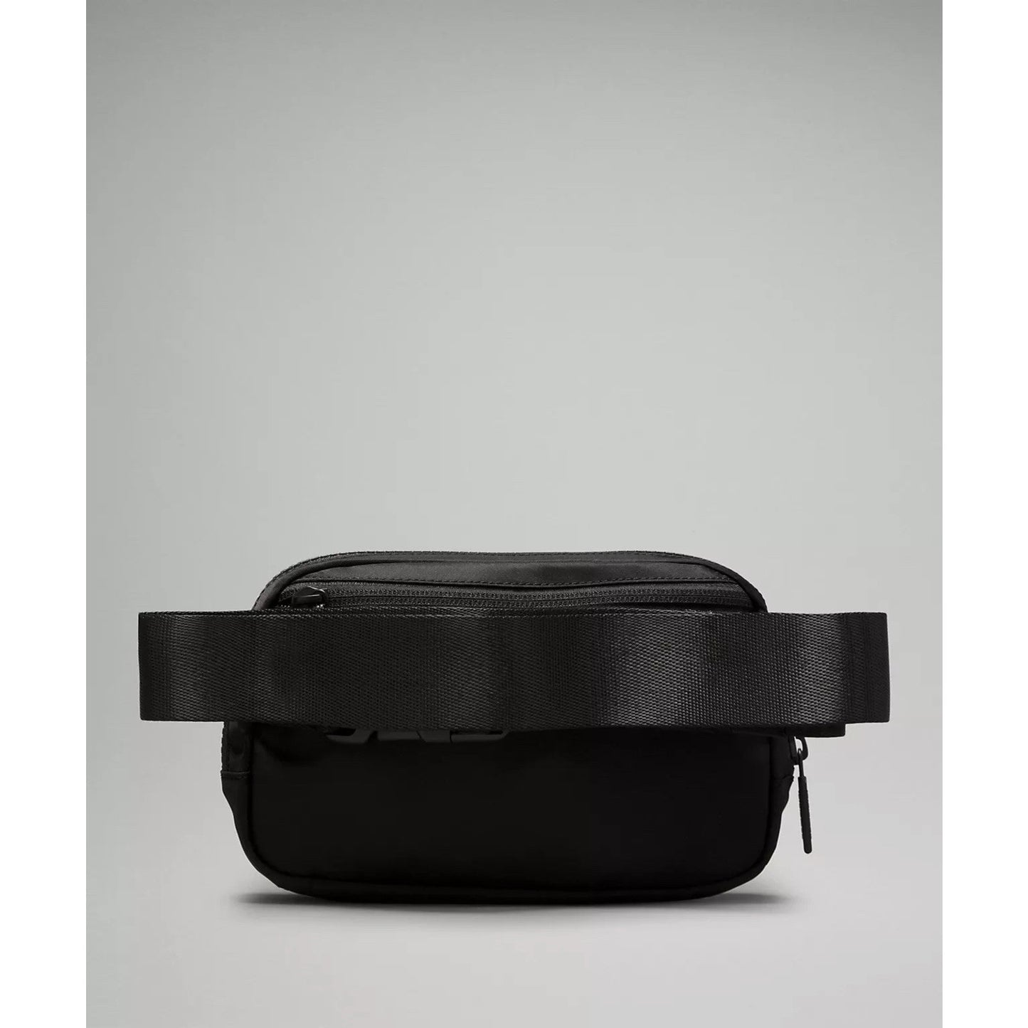 Small black crossbody or waist bag with a wide adjustable strap, rectangular shape, and zipper closure against a plain gray background.