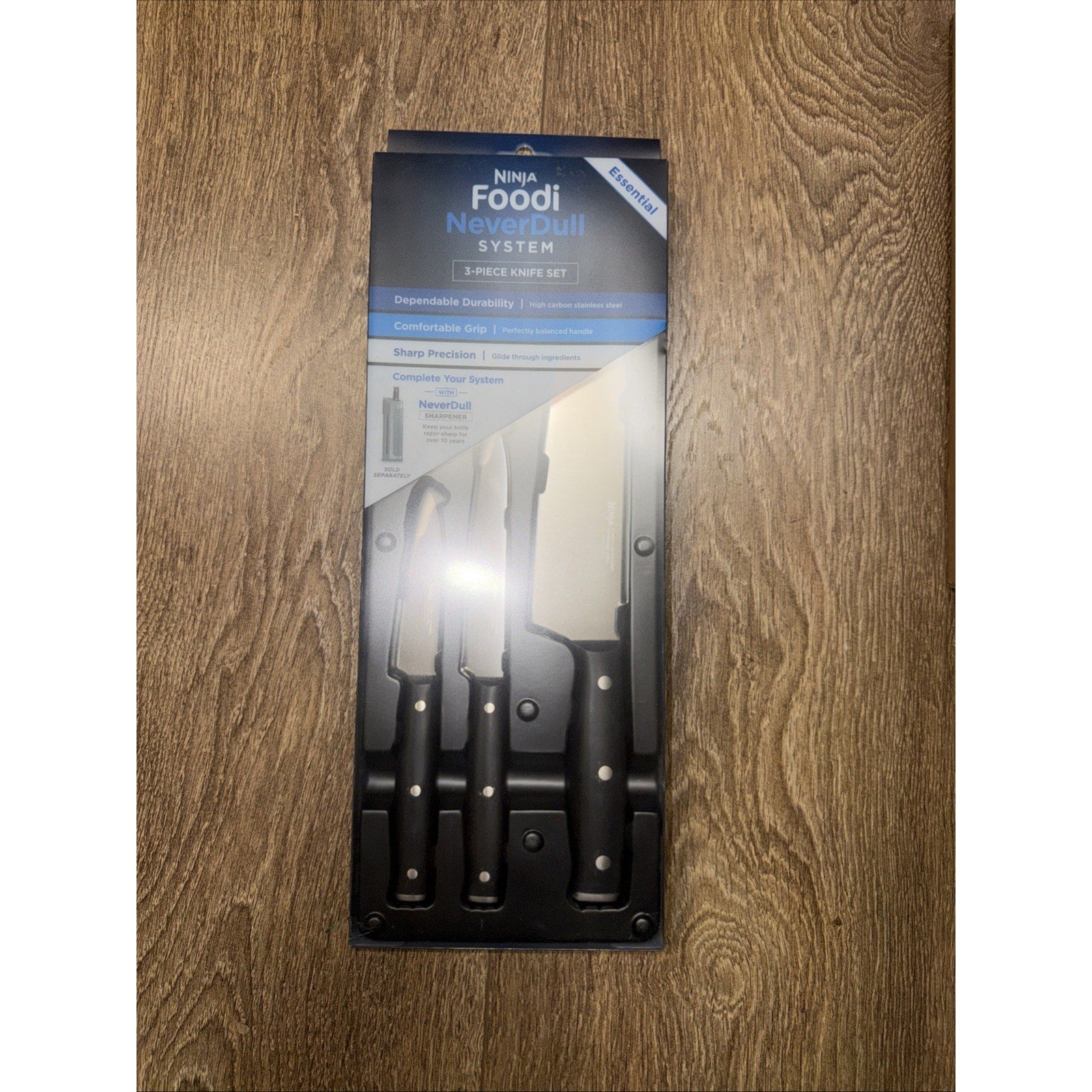 Packaging of a 3-piece kitchen knife set featuring black handles and stainless steel blades, displayed on a wooden surface with product features listed on the box.