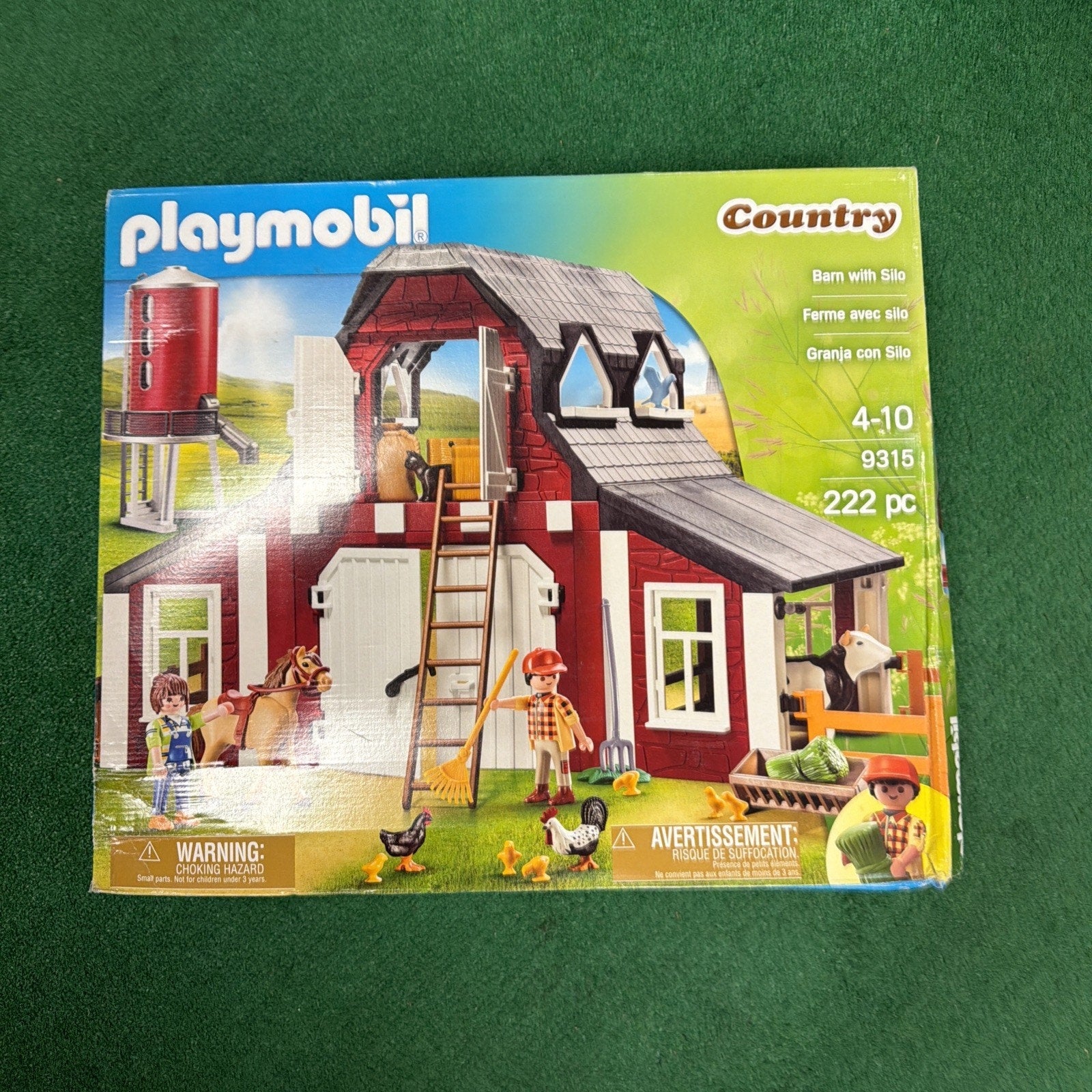 Playmobil Country toy set featuring a red and white barn with silo, farm animals including horses and chickens, three farmer figures, and various farm accessories for ages 4 to 10.