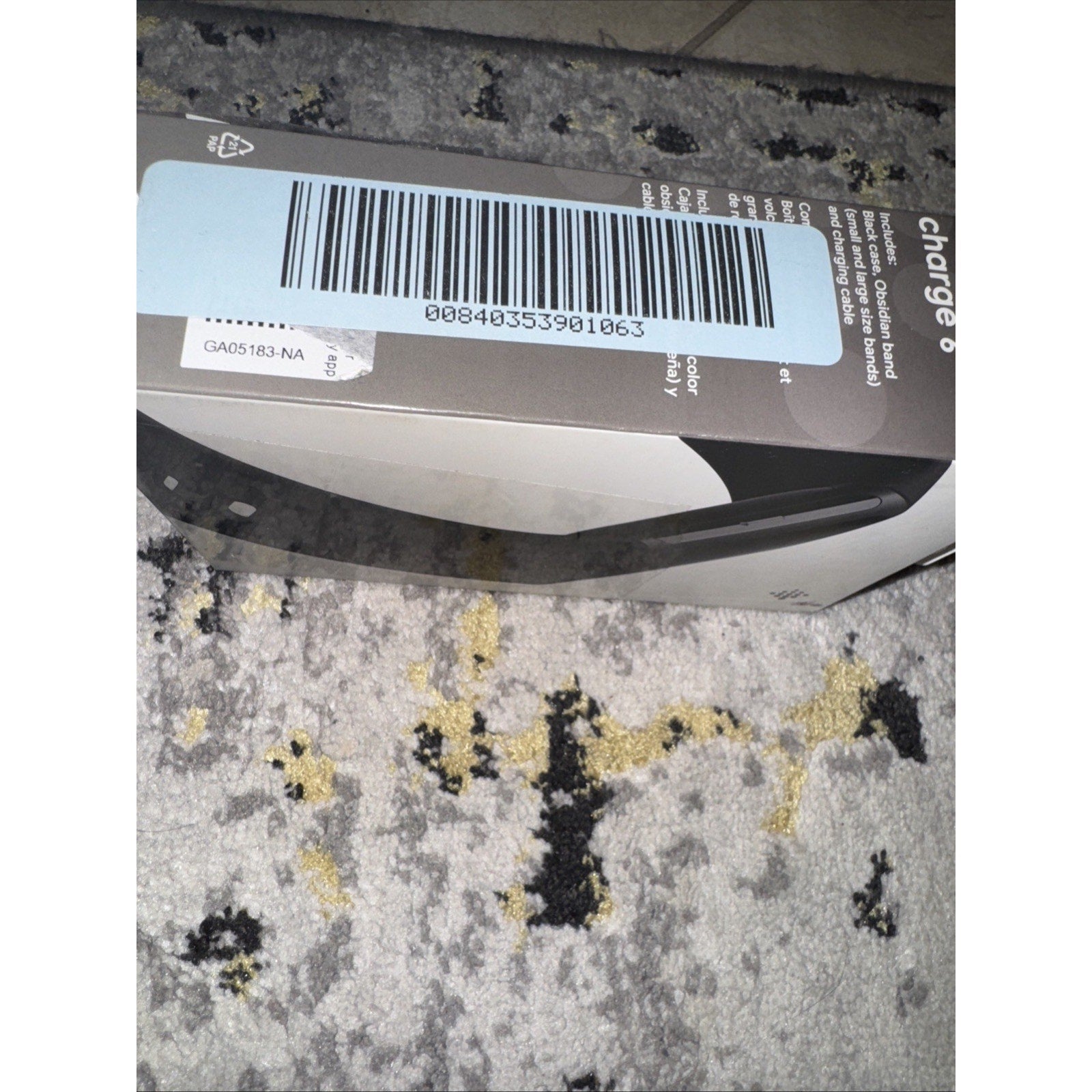 Box packaging of Brand New Fitbit Charge 6 fitness tracker in black with barcode label on carpet background