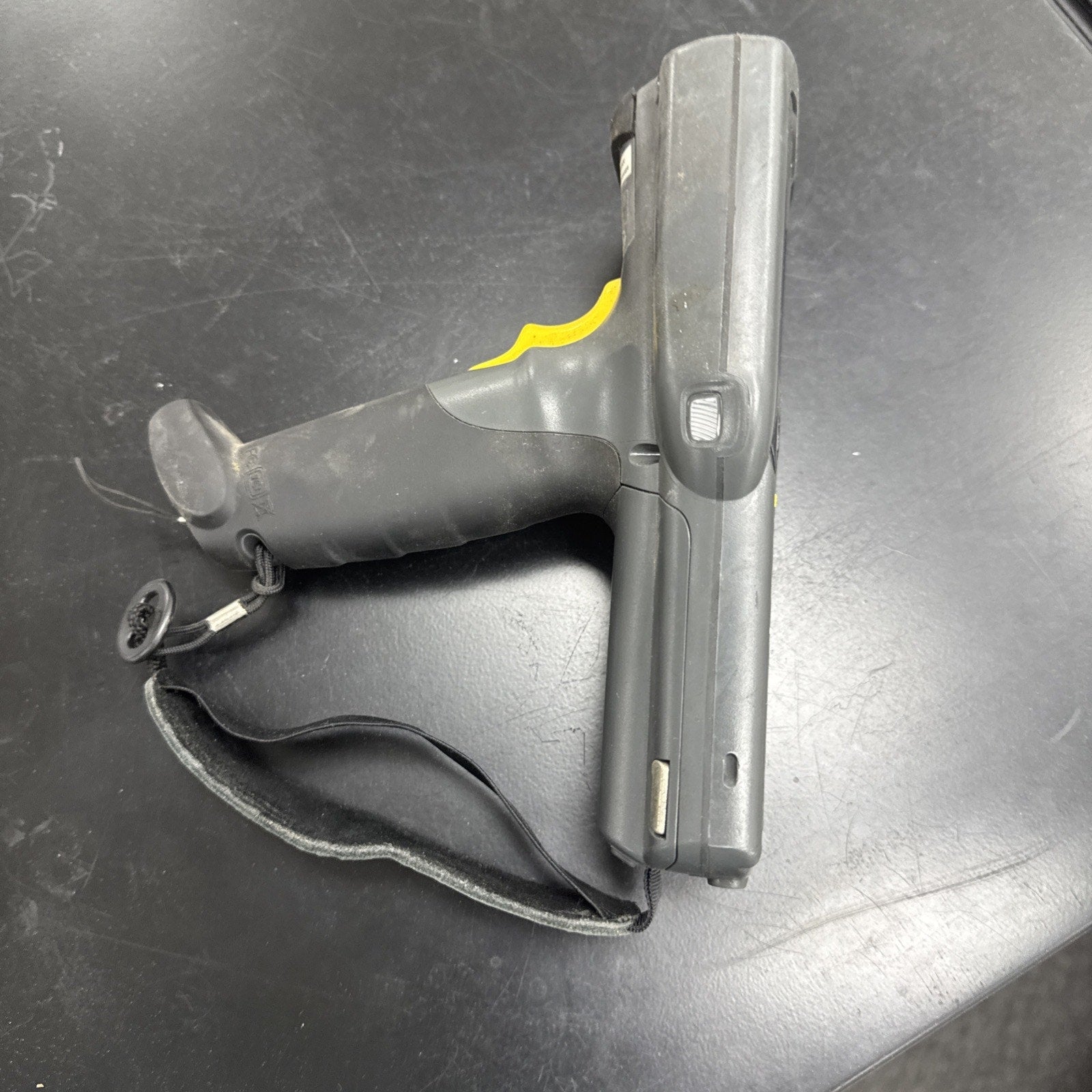 Used Motorola Symbol MC3090 handheld barcode scanner with yellow trigger and wrist strap on black surface