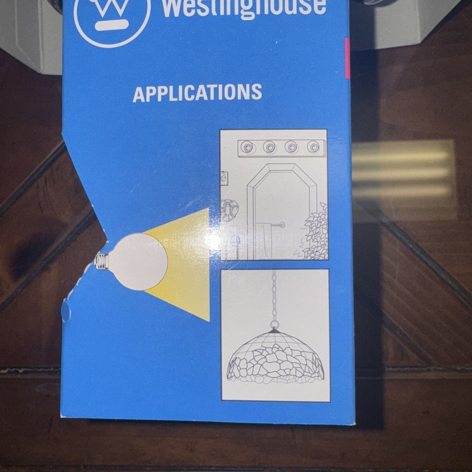 Blue Westinghouse light bulb box showing application illustrations of vanity mirror and hanging lamp fixtures