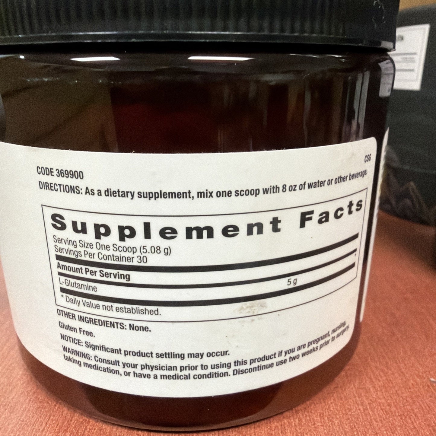 Close-up of a dietary supplement label listing a serving size of one scoop (5.08 g) with 5 g of L-Glutamine, 30 servings per container, gluten-free, and usage directions.