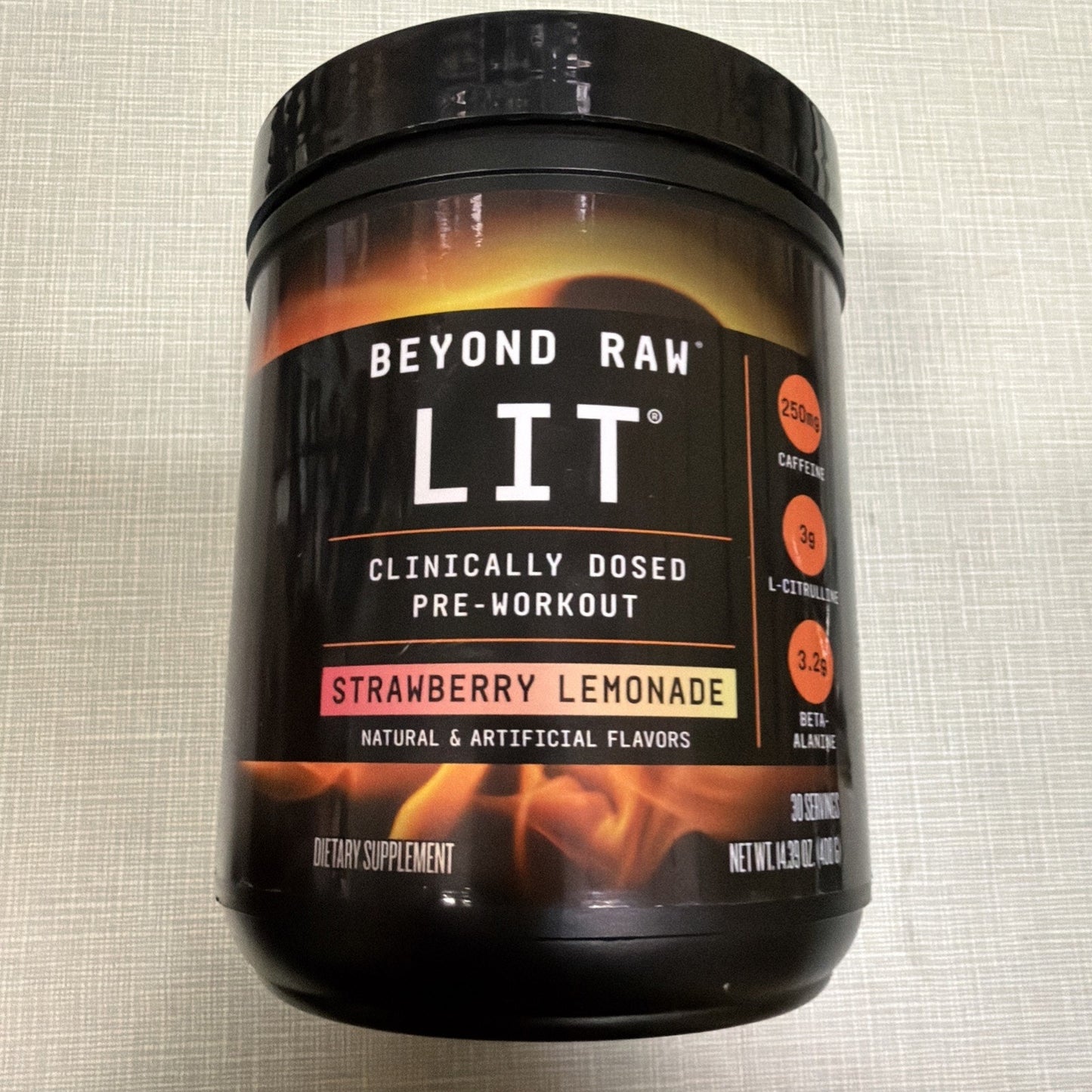 Black container of Beyond Raw LIT pre-workout supplement in Strawberry Lemonade flavor, featuring nutrient dosages and flame graphic on the label.