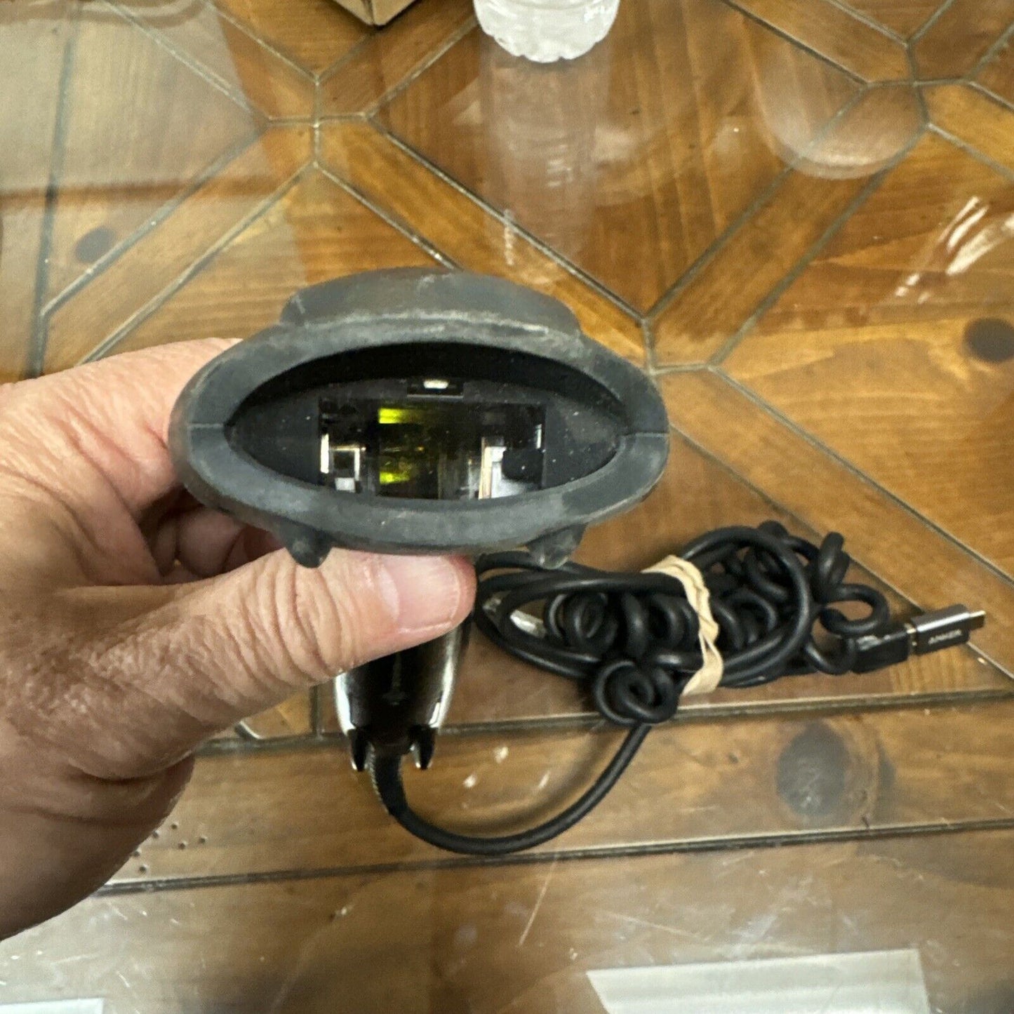 Used Honeywell USB barcode scanner held over wooden table with coiled cable and USB connector visible