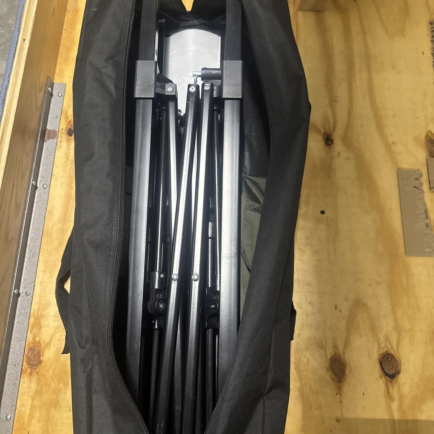 Eagle Peak 4x4 pop up canopy tent frame neatly folded inside black carry bag on wooden surface