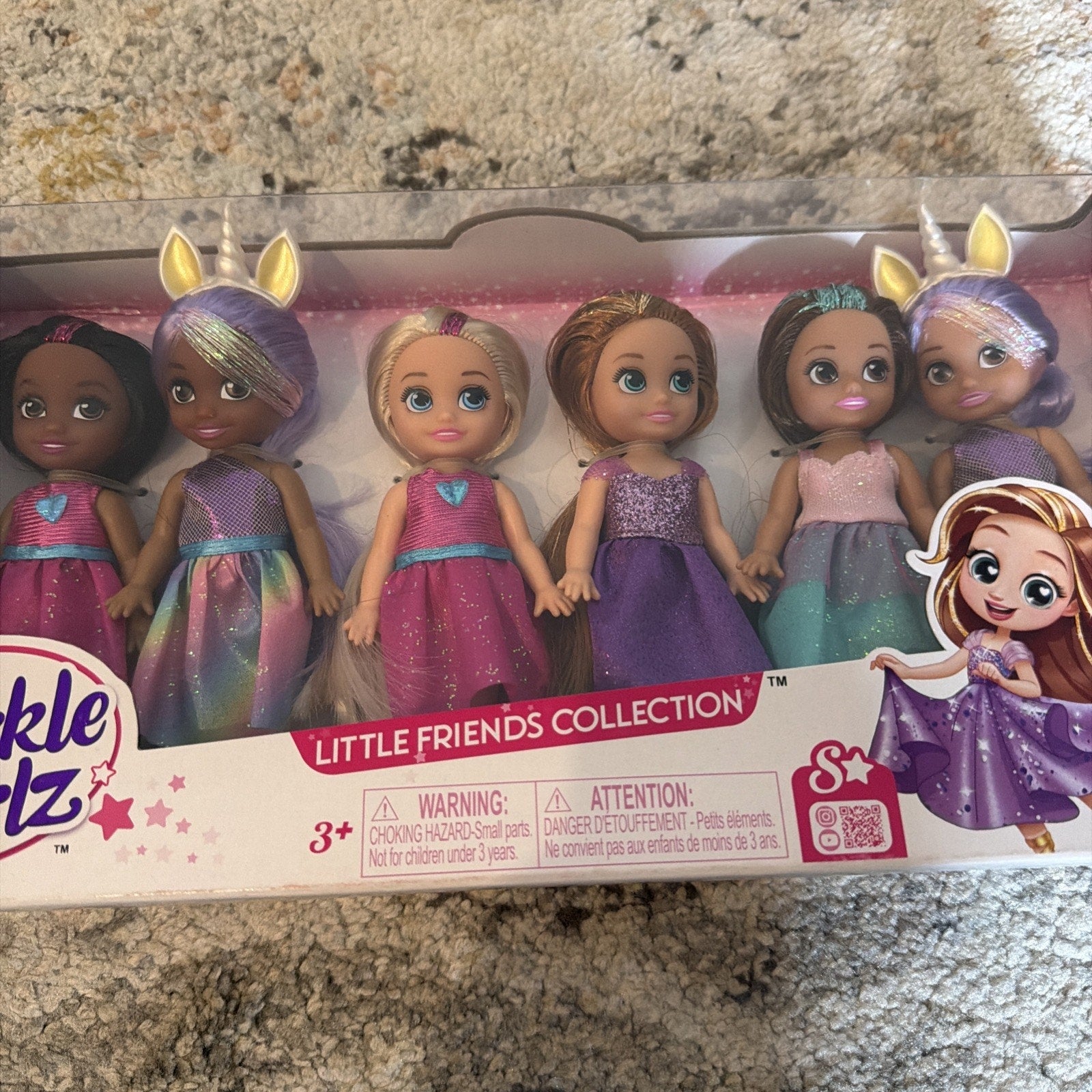Set of six small dolls with varied skin tones and colorful dresses in shades of purple, pink, and blue, packaged in a clear box labeled "Little Friends Collection.