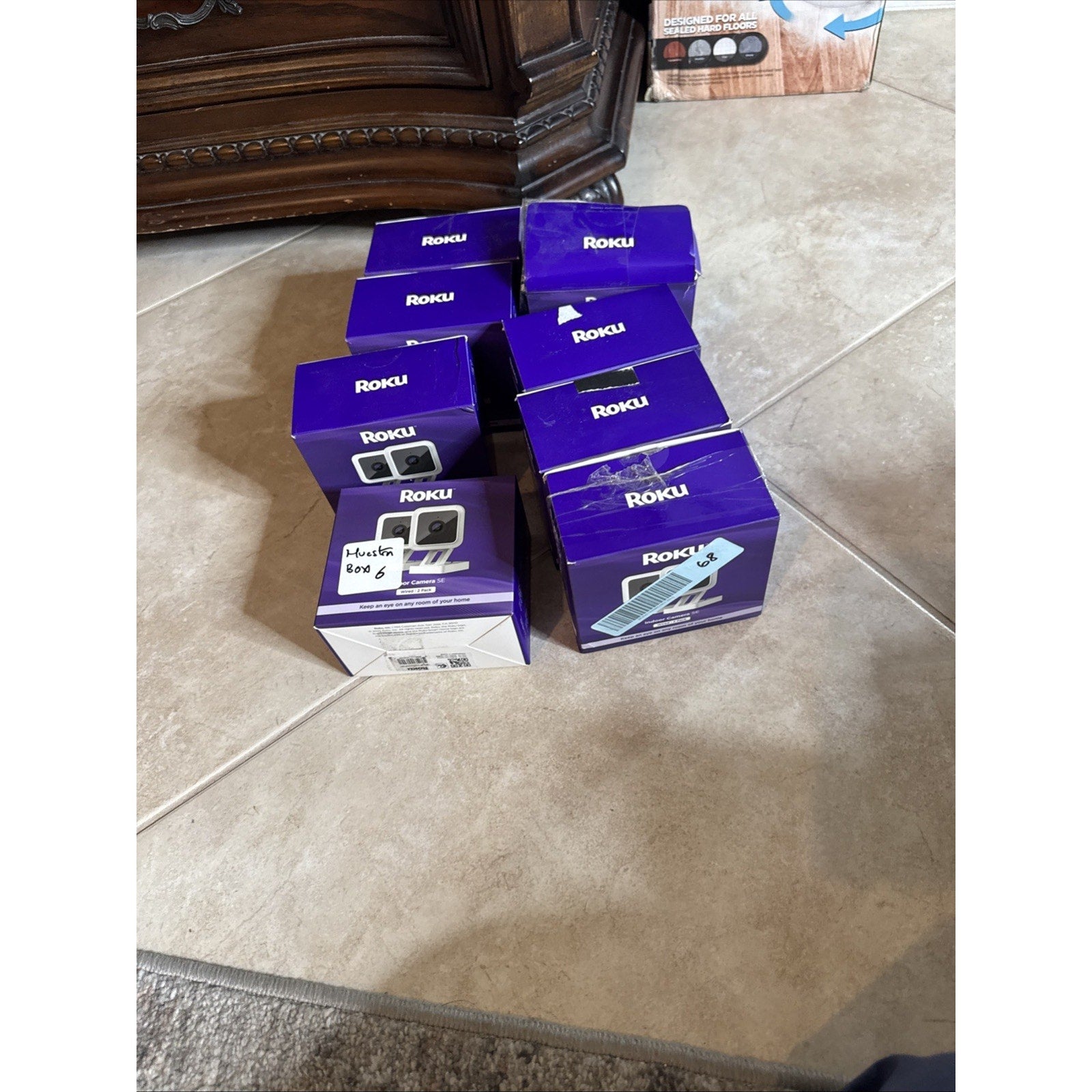 Multiple Roku Indoor Camera SE wired 2 pack boxes stacked on tiled floor ready for shipping or storage