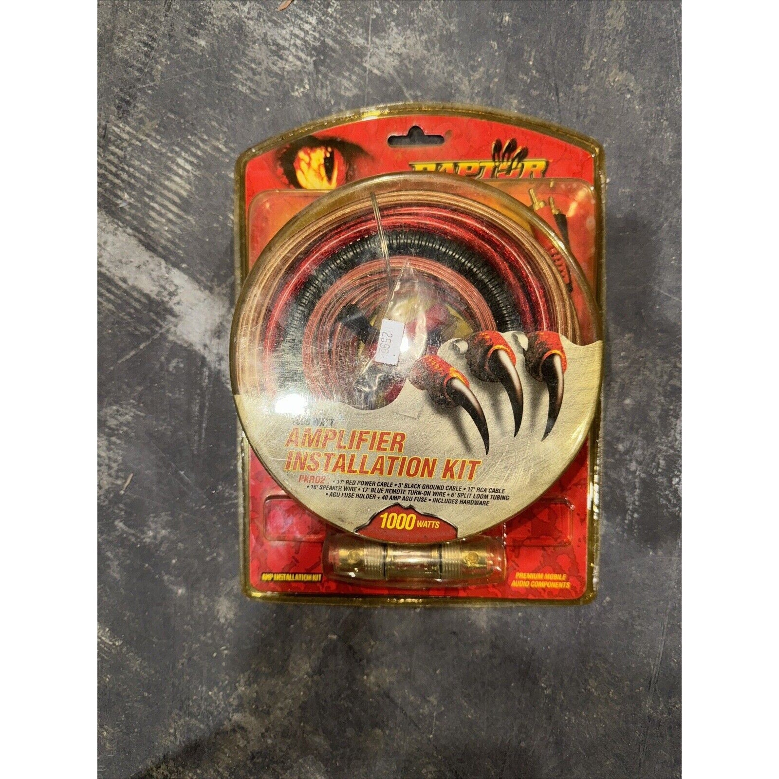 Raptor amplifier installation kit with cables and fuse holder in red and black packaging showing claw design and 1000 watt power rating
