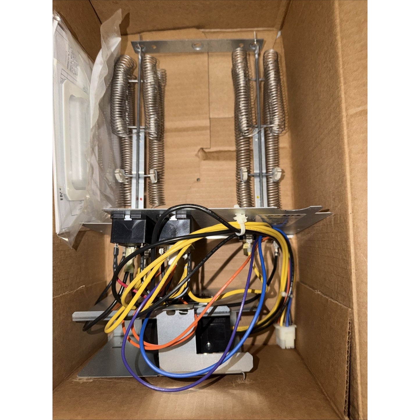 Metal heating element assembly with dual coiled wire tubes, mounted on a metal frame, connected to multiple colored electrical wires inside a brown cardboard box.