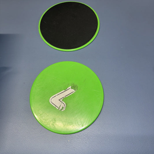 Green and black exercise sliders for fitness workouts with smooth surfaces and circular design on blue mat background
