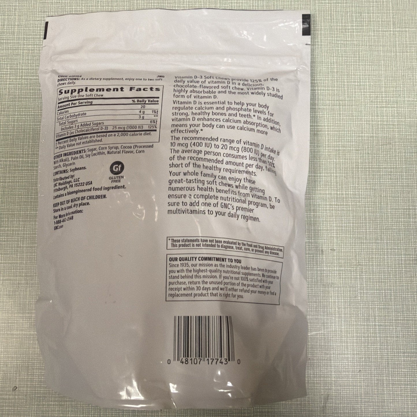 Back of a white resealable supplement pouch showing detailed nutrition facts, ingredient list, vitamin D-3 health benefits text, allergen warnings, barcode, and quality commitment statement.