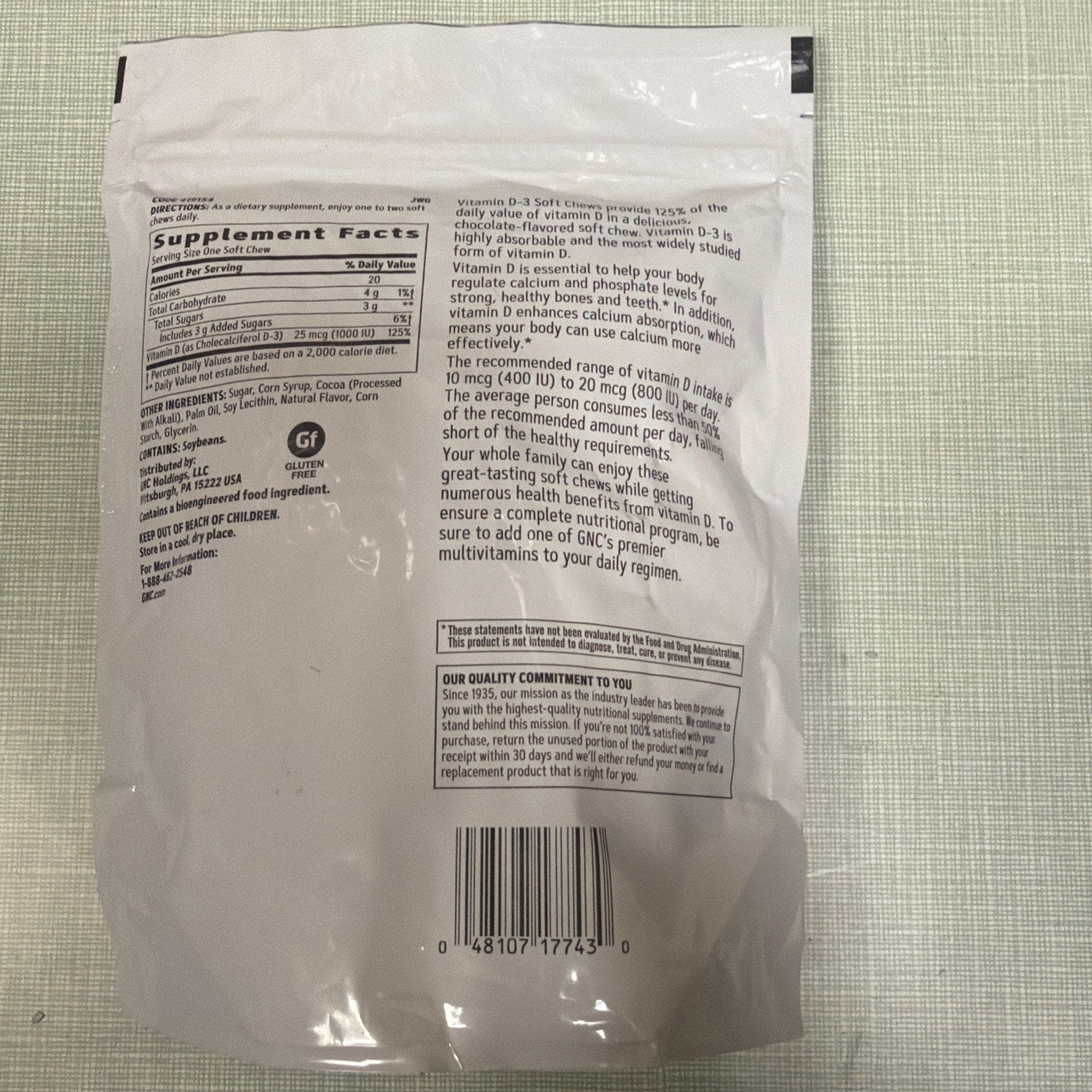 Back of a white resealable supplement pouch showing detailed nutrition facts, ingredient list, vitamin D-3 health benefits text, allergen warnings, barcode, and quality commitment statement.