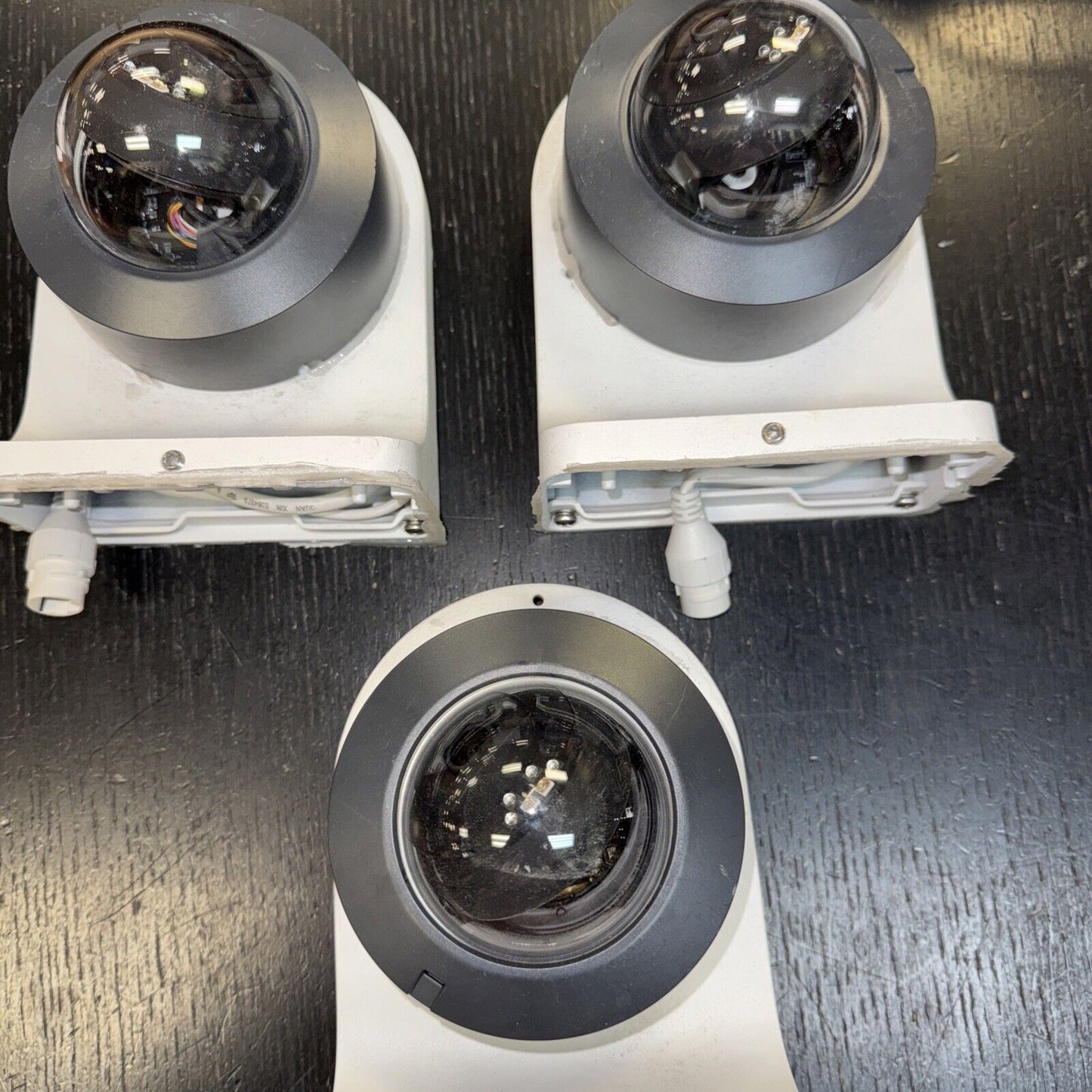 Lot of three Alarm.com dome surveillance cameras with infrared and mounting bases on black surface