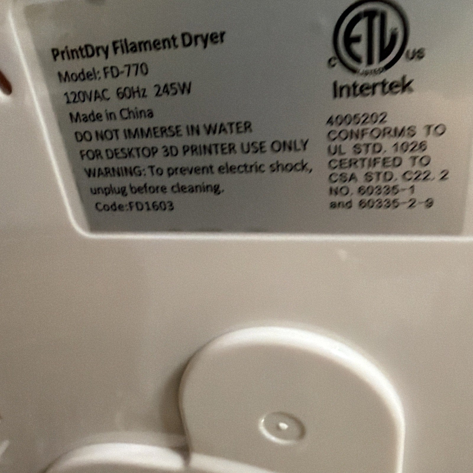 Close-up of a white plastic label on a PrintDry Filament Dryer showing model number FD-770, electrical specifications, safety warnings, certification marks, and manufacturing details.