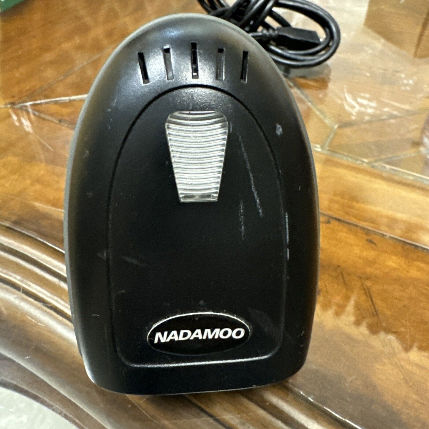 Nadamoo black wireless handheld barcode scanner with brand logo and charging cable on wooden surface close-up view