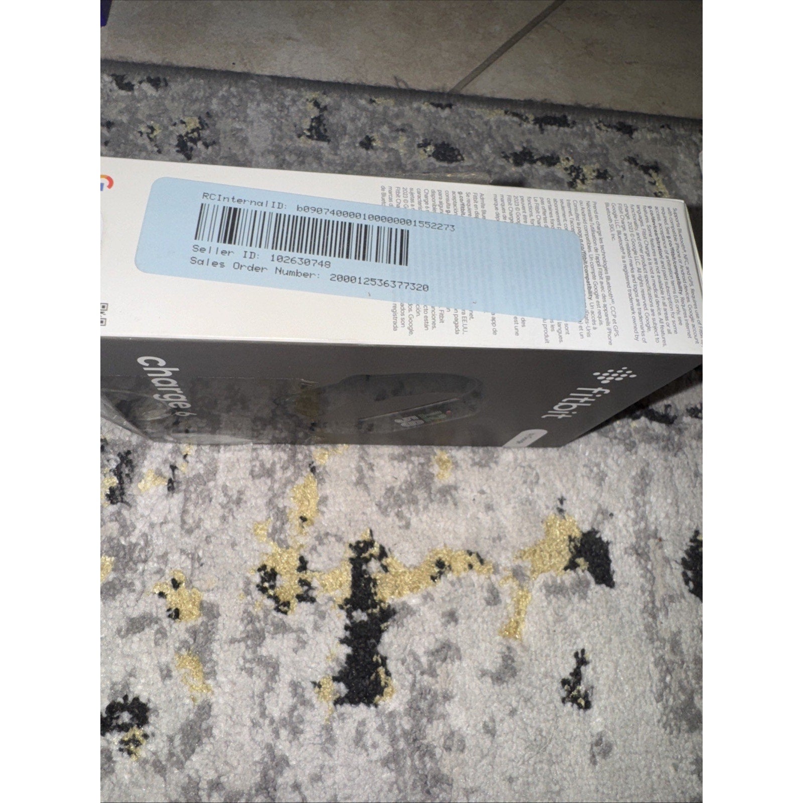 Box of Brand New Fitbit Charge 6 Fitness Tracker in black placed on patterned carpet floor