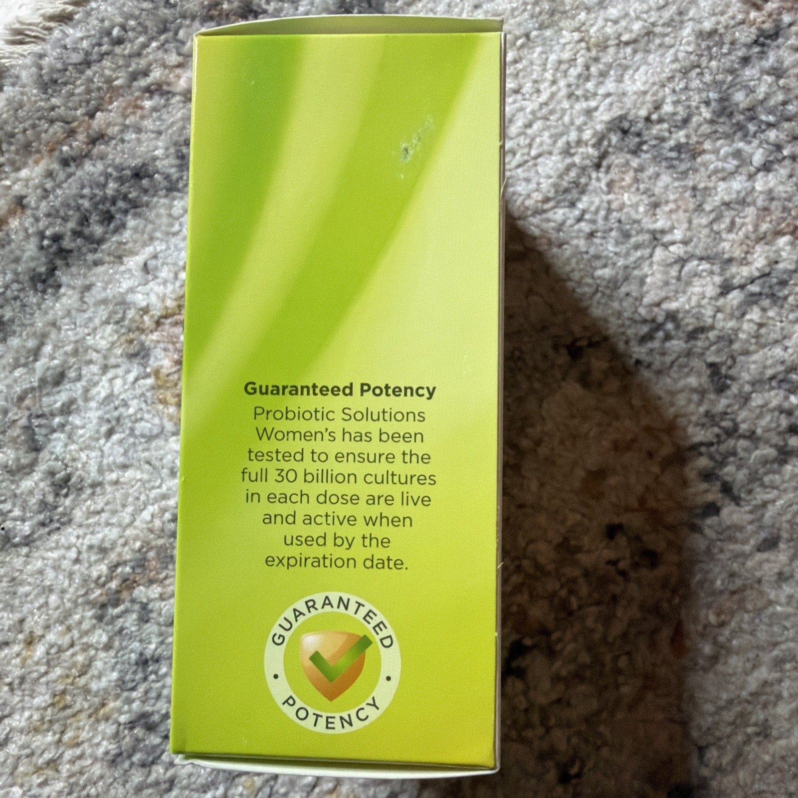 Side view of a green supplement box highlighting guaranteed potency for Probiotic Solutions Women's, ensuring 30 billion live cultures per dose through the expiration date.