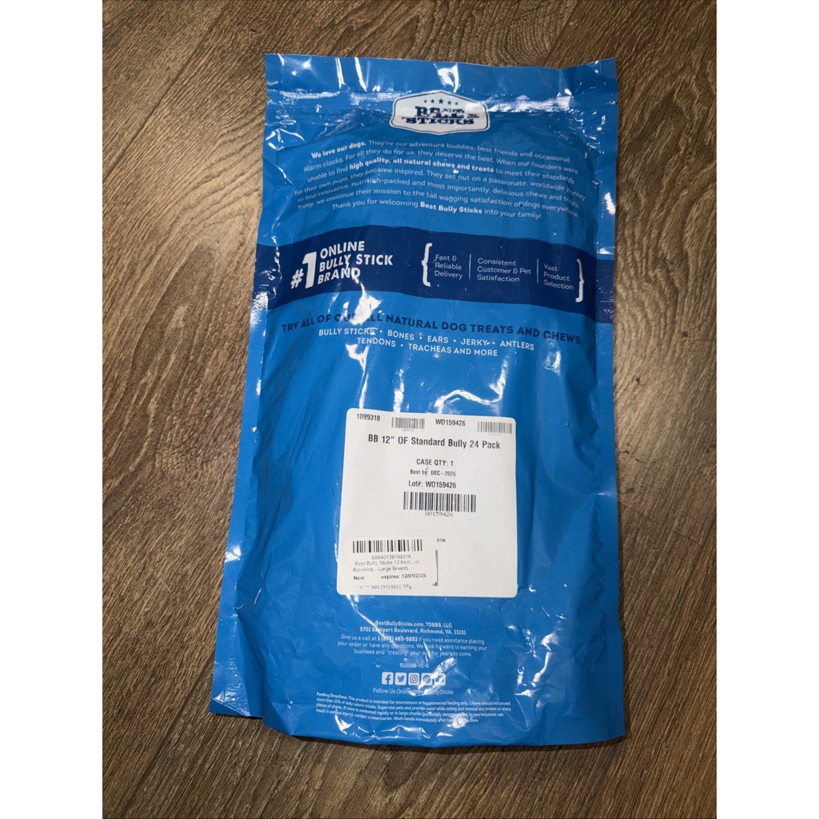 Blue resealable packaging bag for natural dog treats and chews, featuring product information, brand logo, and a white label with batch and barcode details on a wooden surface.