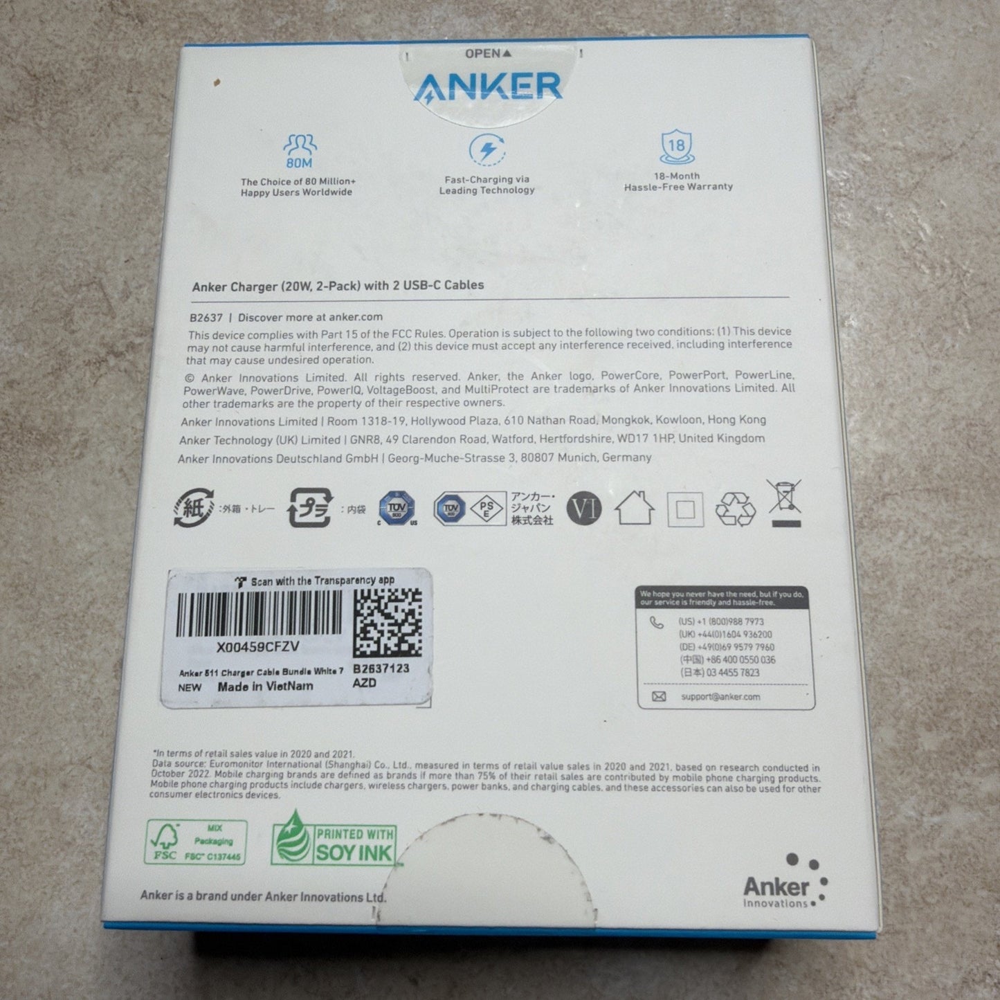 Back of Anker charger box displaying product details, certification logos, barcodes, and text about safety, compliance, and manufacturing information on a white background.
