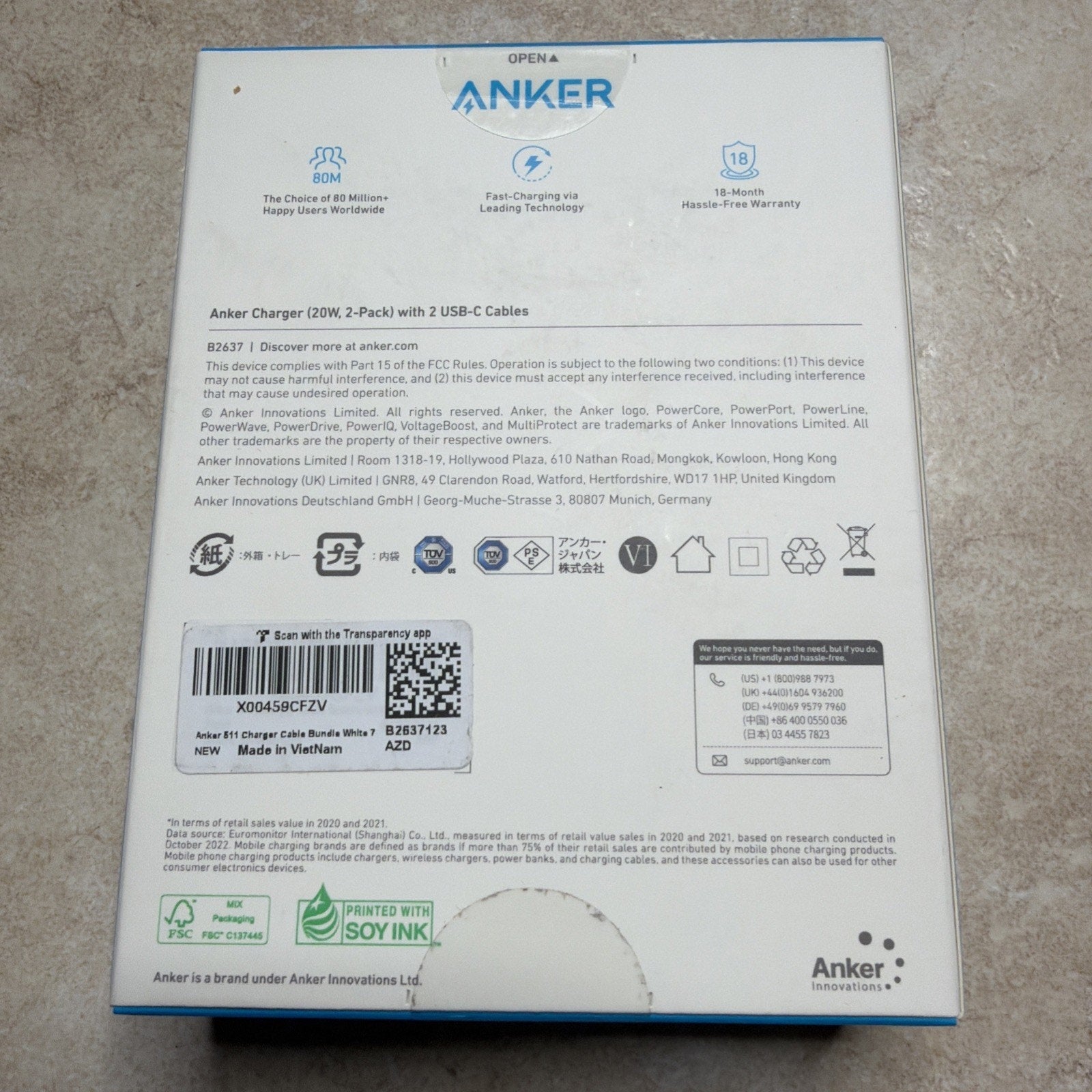 Back of Anker charger box displaying product details, certification logos, barcodes, and text about safety, compliance, and manufacturing information on a white background.
