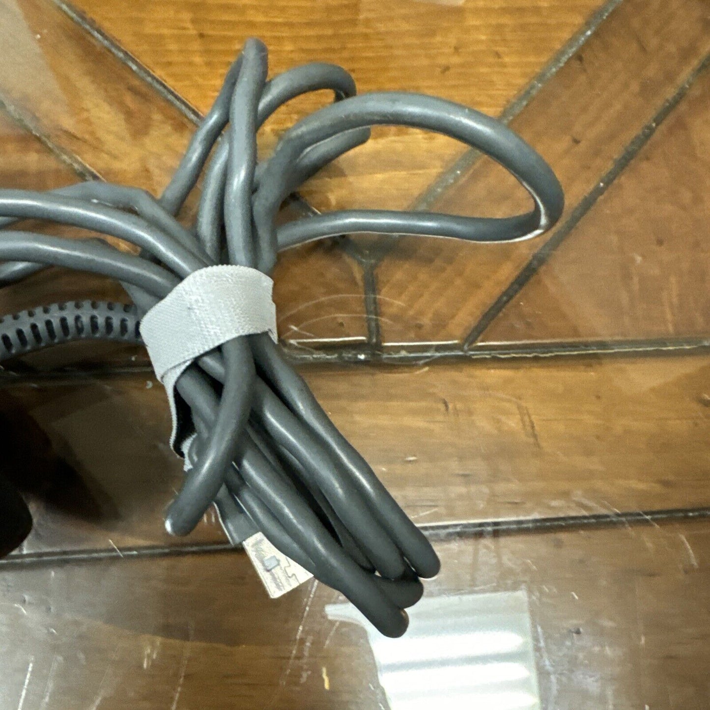 Coiled gray cable attached to Motorola Reader Scanner DS4208-DL0007WR on wooden surface without box