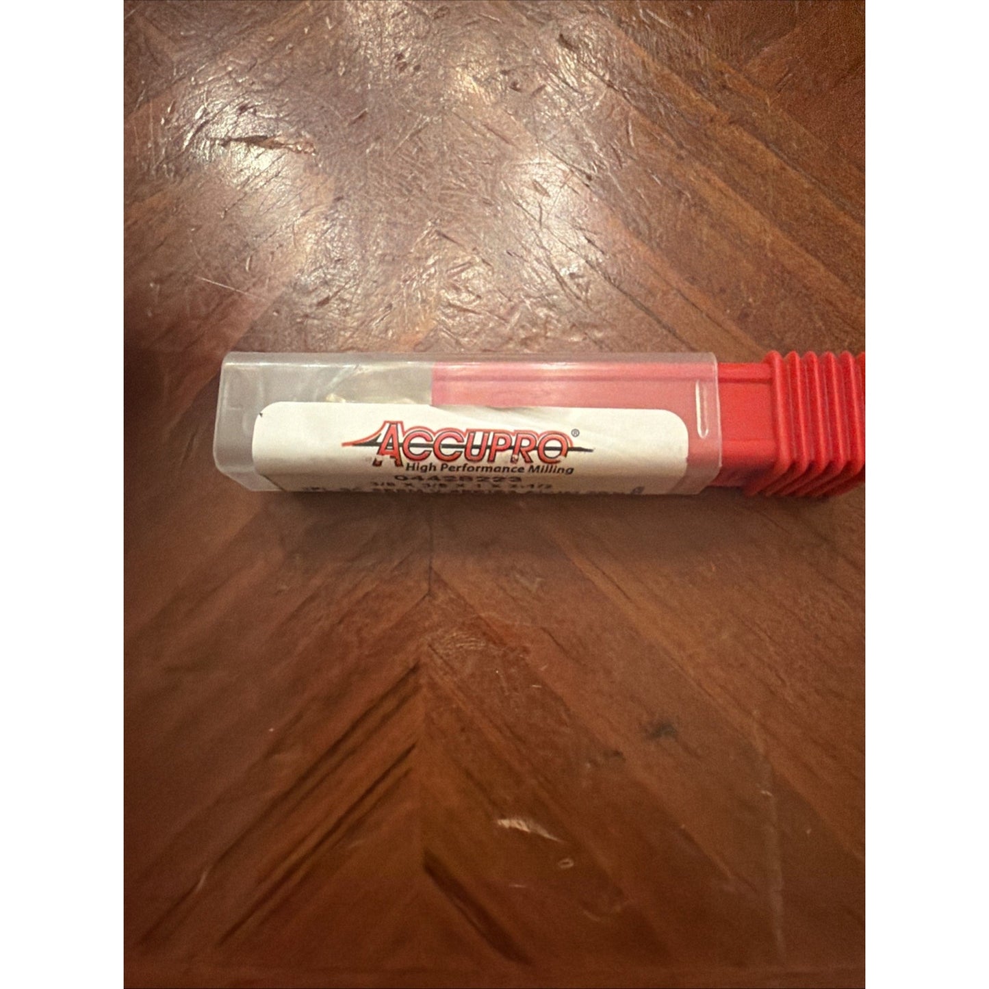 Clear plastic and red metal container labeled with "AccuPro High Performance Milling" placed on a brown wooden surface with visible grain patterns.