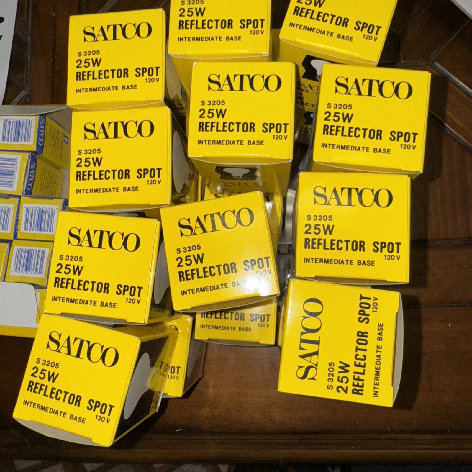 Lot of 23 new Satco 25W 120V S3205 reflector spot light bulbs with intermediate base in yellow boxes stacked on surface