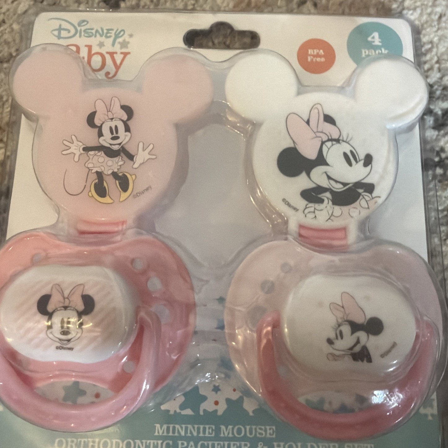 Pack of four Minnie Mouse themed orthodontic pacifiers and holders, two with white and pink designs featuring Minnie in various poses, packaged on a card backing.