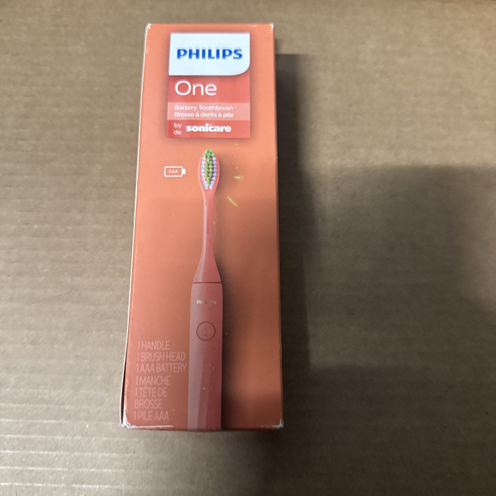 Philips One Sonicare electric toothbrush in coral color with 90 days battery life shown in damaged box packaging