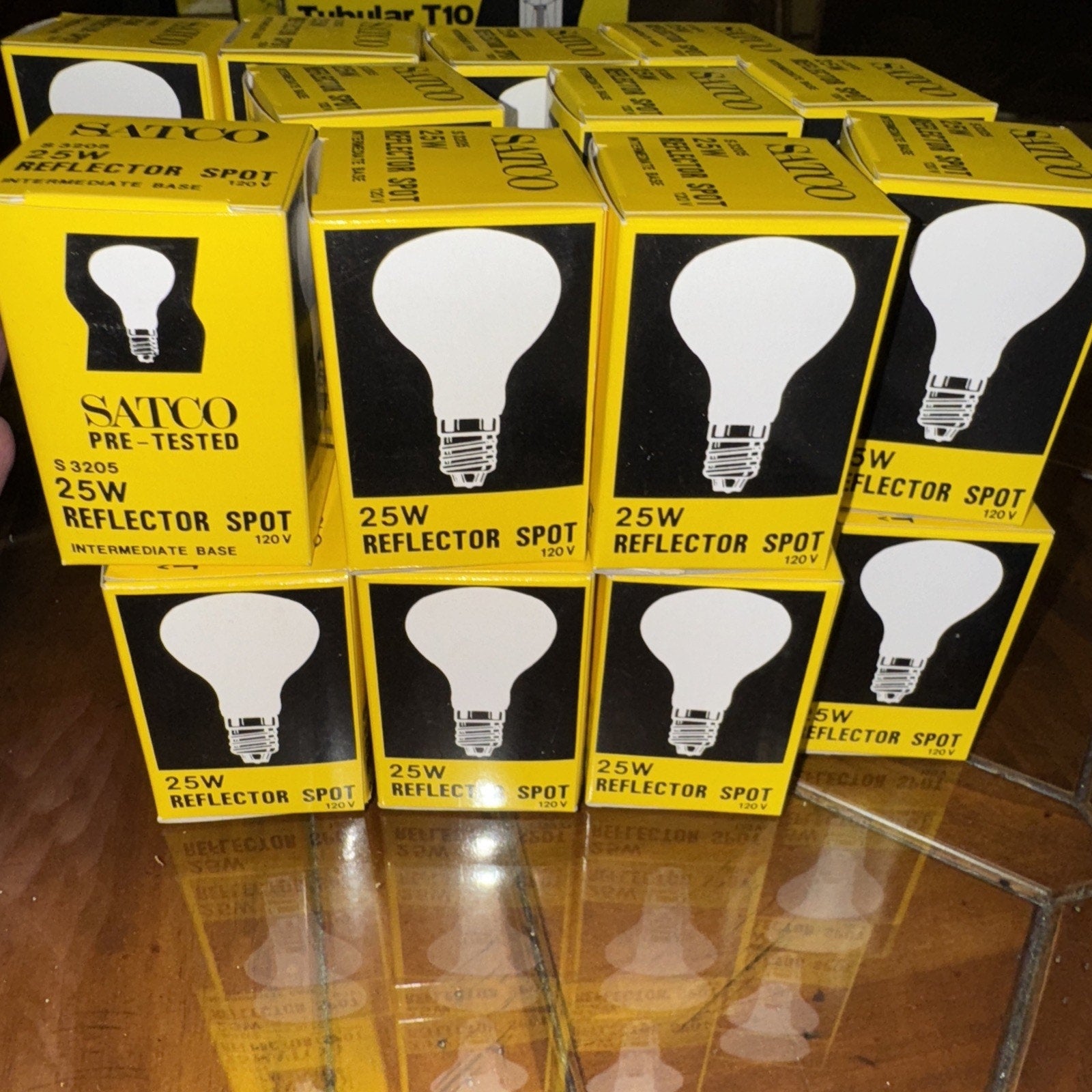 Lot of 23 new Satco 25W 120V S3205 reflector spot light bulbs in yellow and black packaging stacked on reflective surface