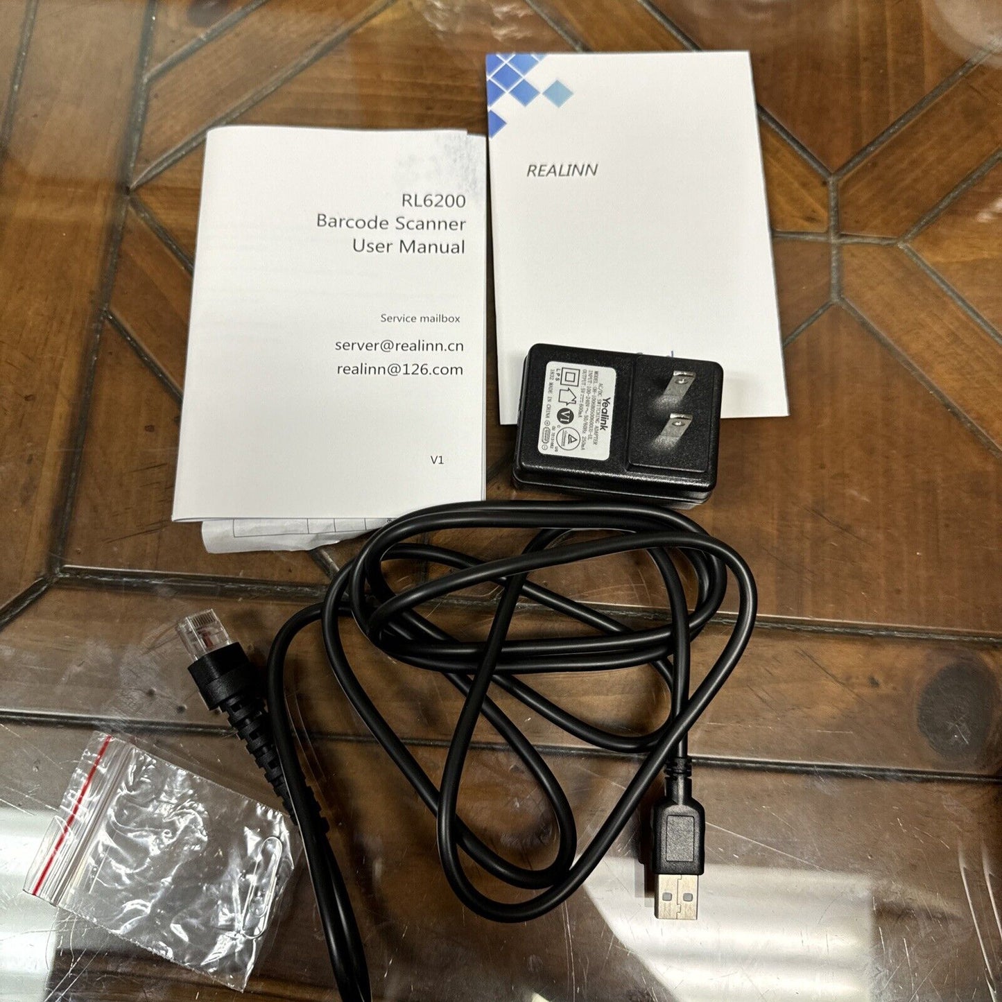 Realinn RL6200 barcode scanner USB charging cable power adapter user manual and small plastic bag on wooden surface