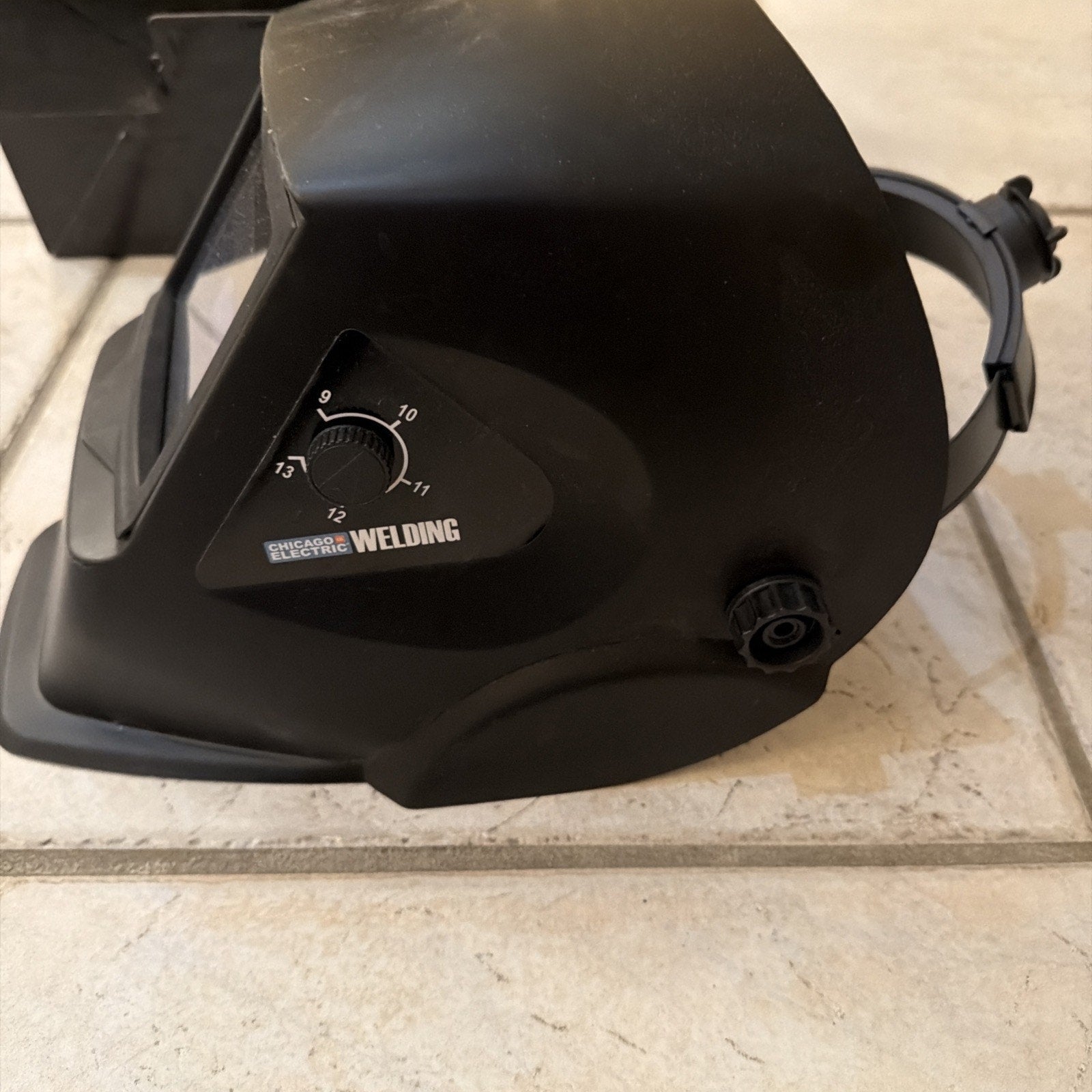 Chicago Electric black auto-darkening welding helmet with adjustable shade control dial and headgear strap